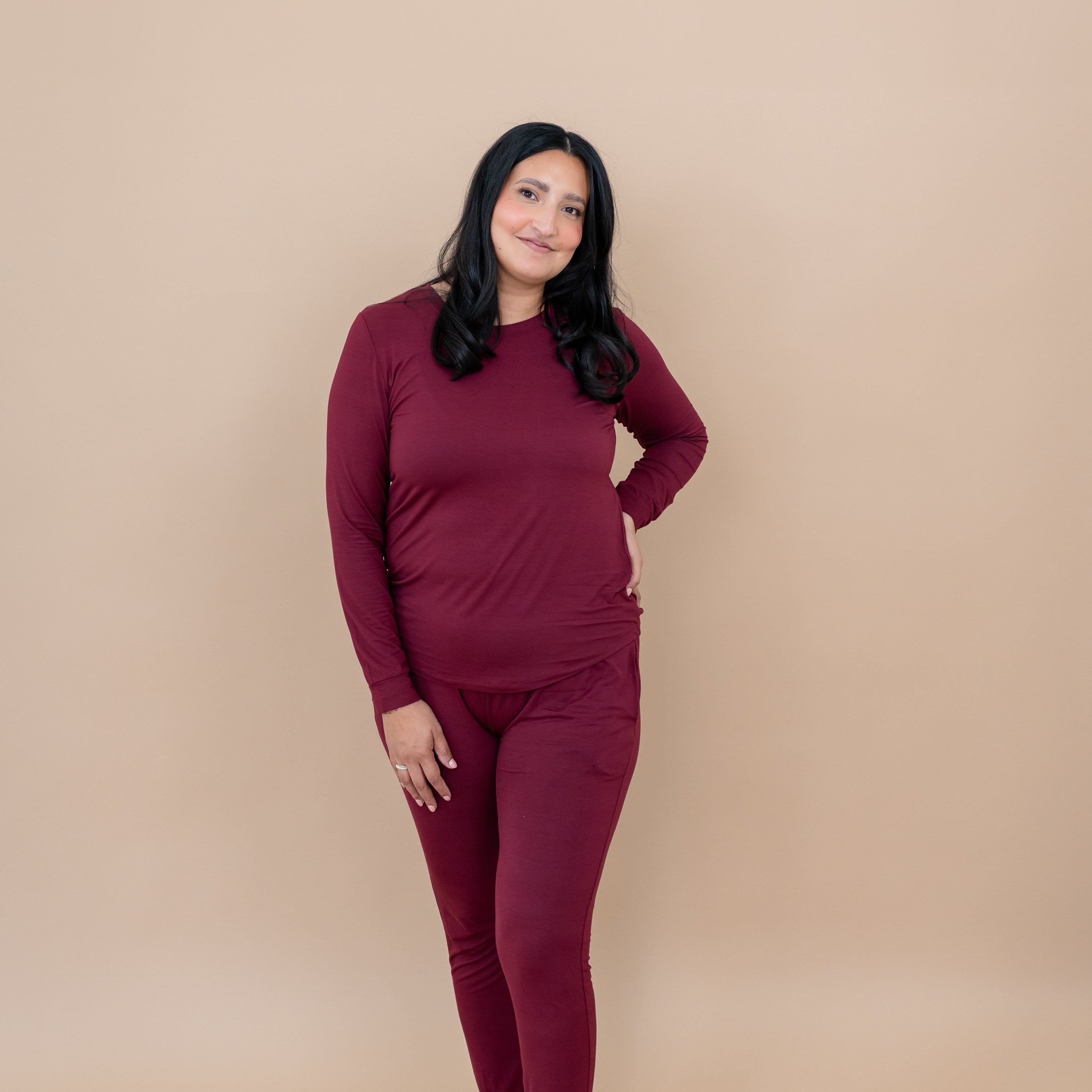 Smiling female model standing with one hand on hip wearing the Women's Jogger Pajama Set in Burgundy