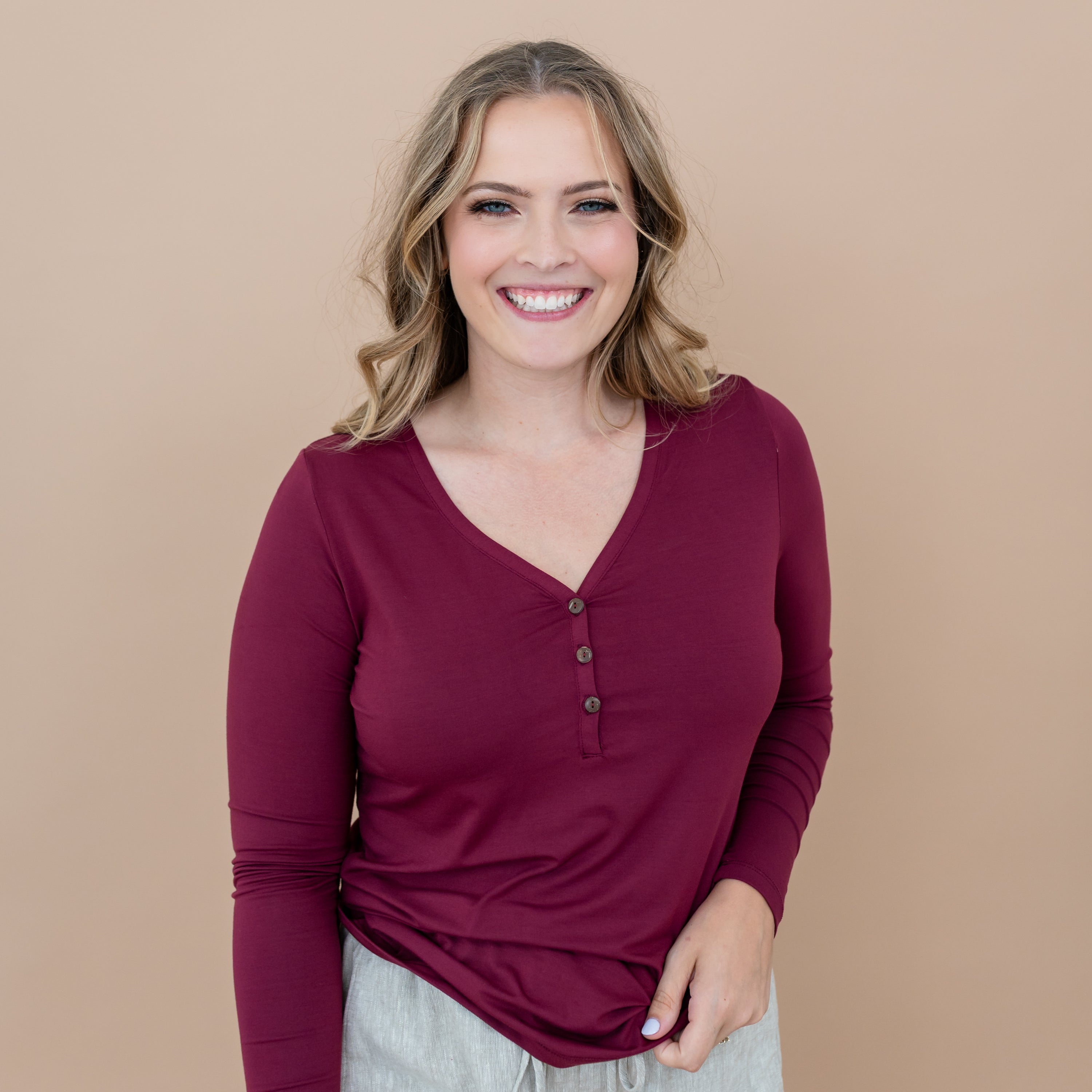 Smiling female model wearing the Women's Long Sleeve Henley Tee in Burgundy