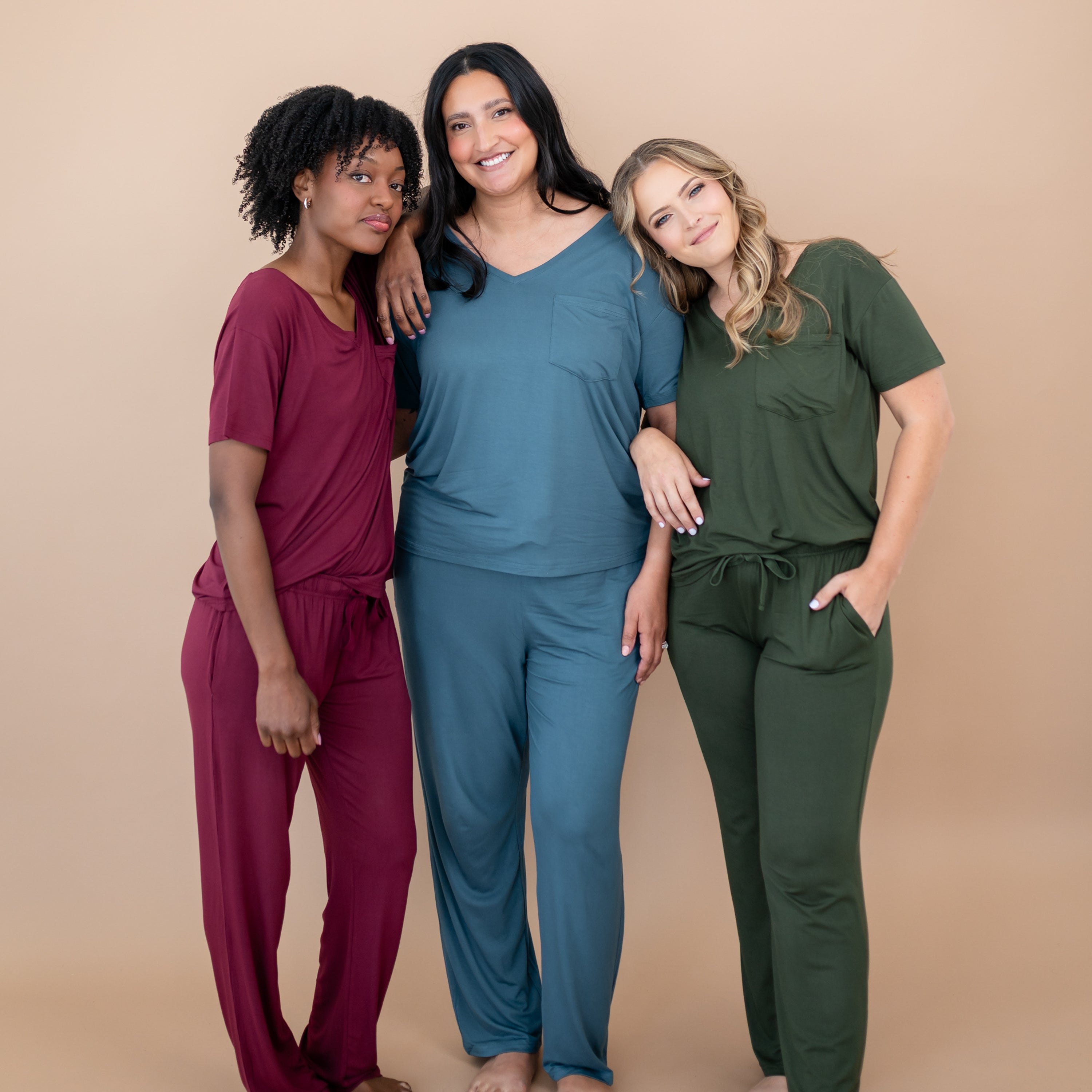 Three women wearing matching outfits in red, blue, and green on a beige background
