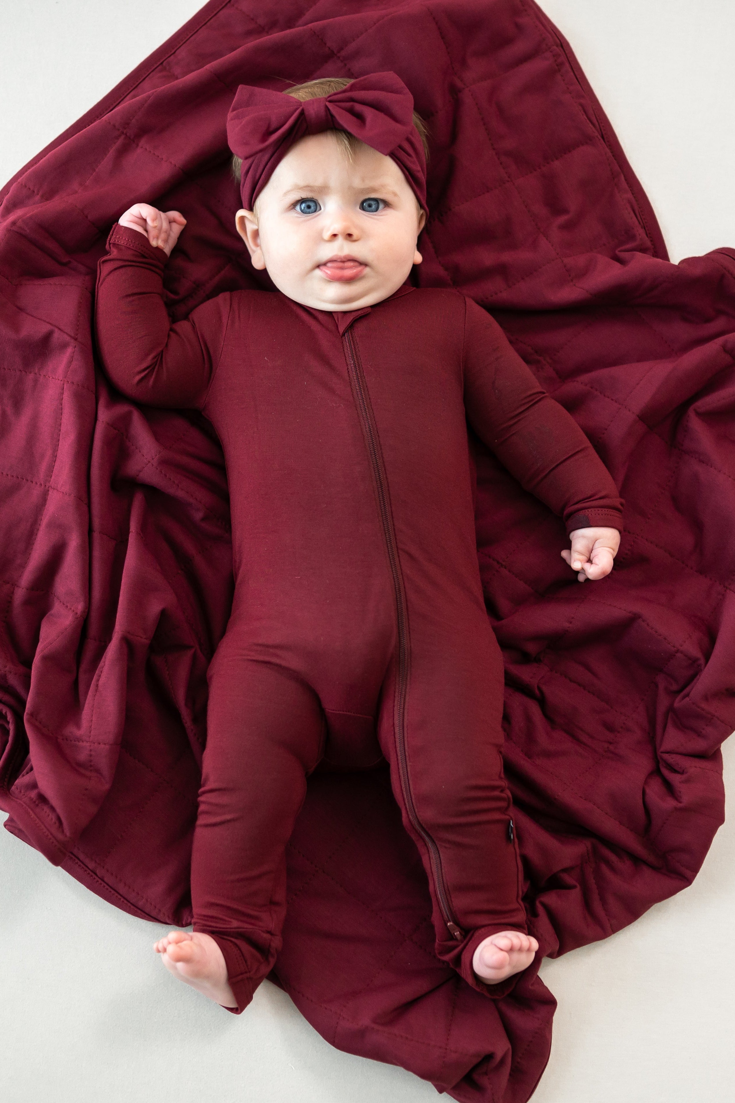 Infant laying on a Baby Blanket in Burgundy 1.0 wearing matching romper pajamas