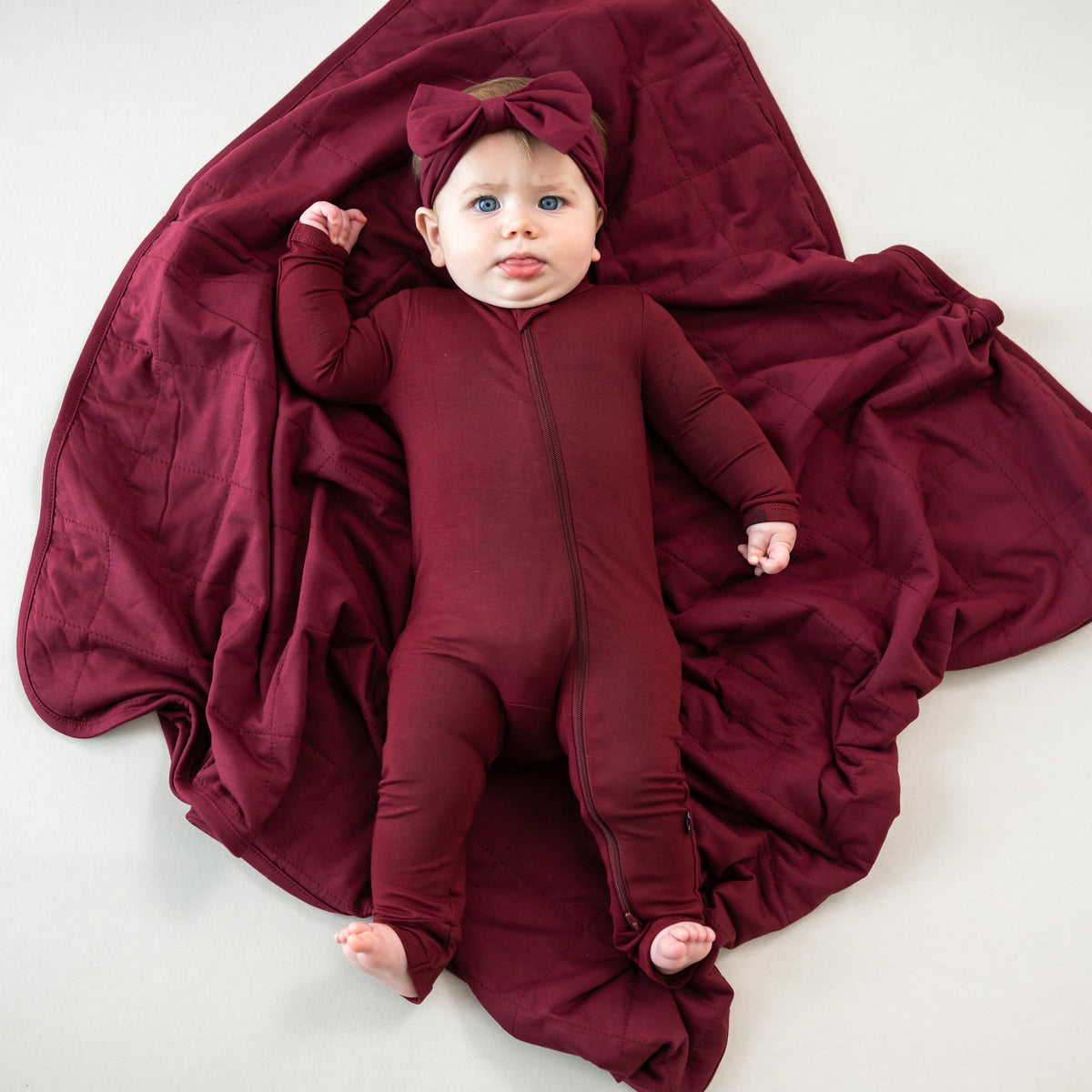 Infant laying on a Baby Blanket in Burgundy 1.0 wearing matching romper pajamas