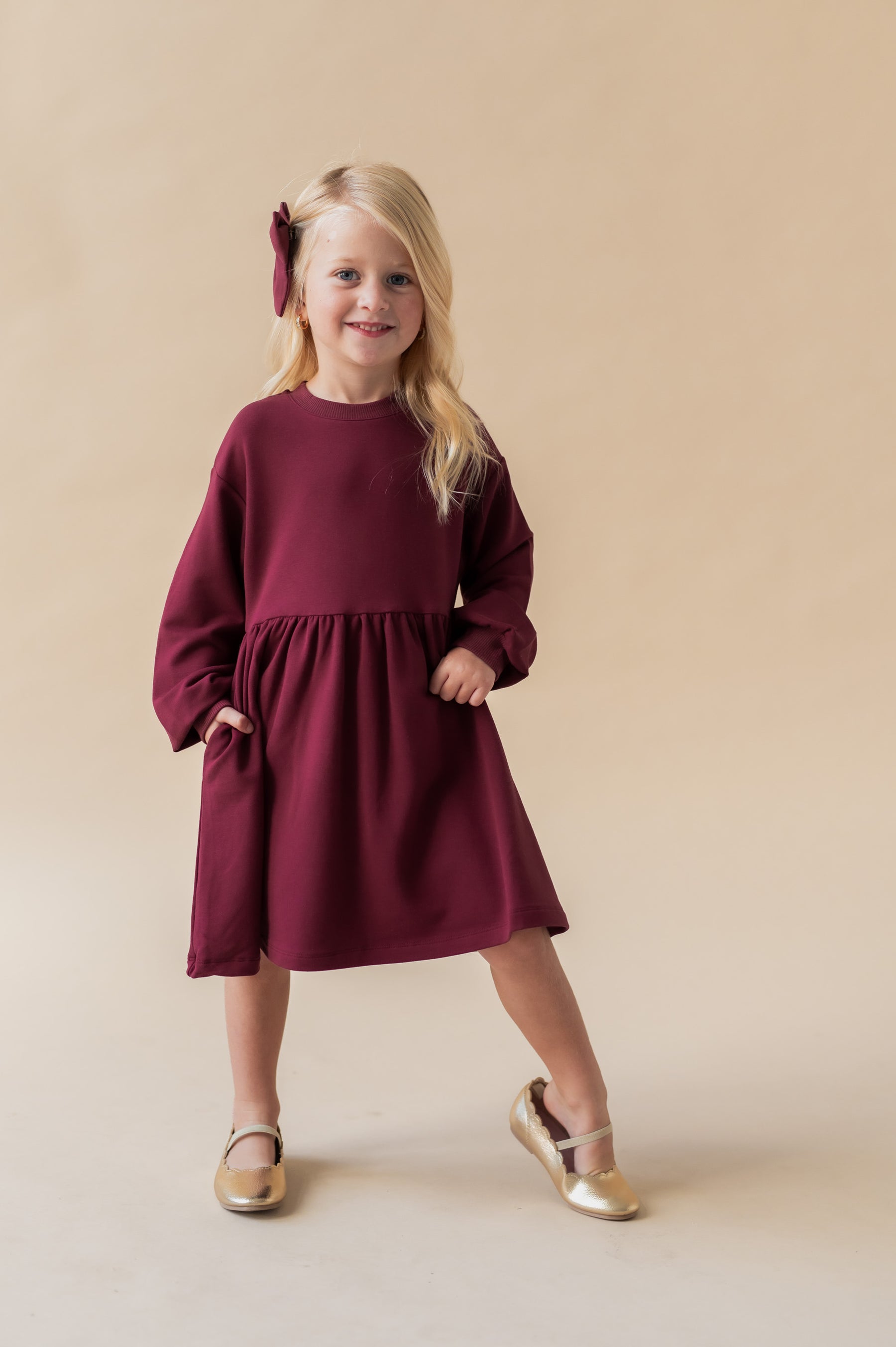 Girl posing in Long Sleeve Skater Dress in Burgundy color on a beige background