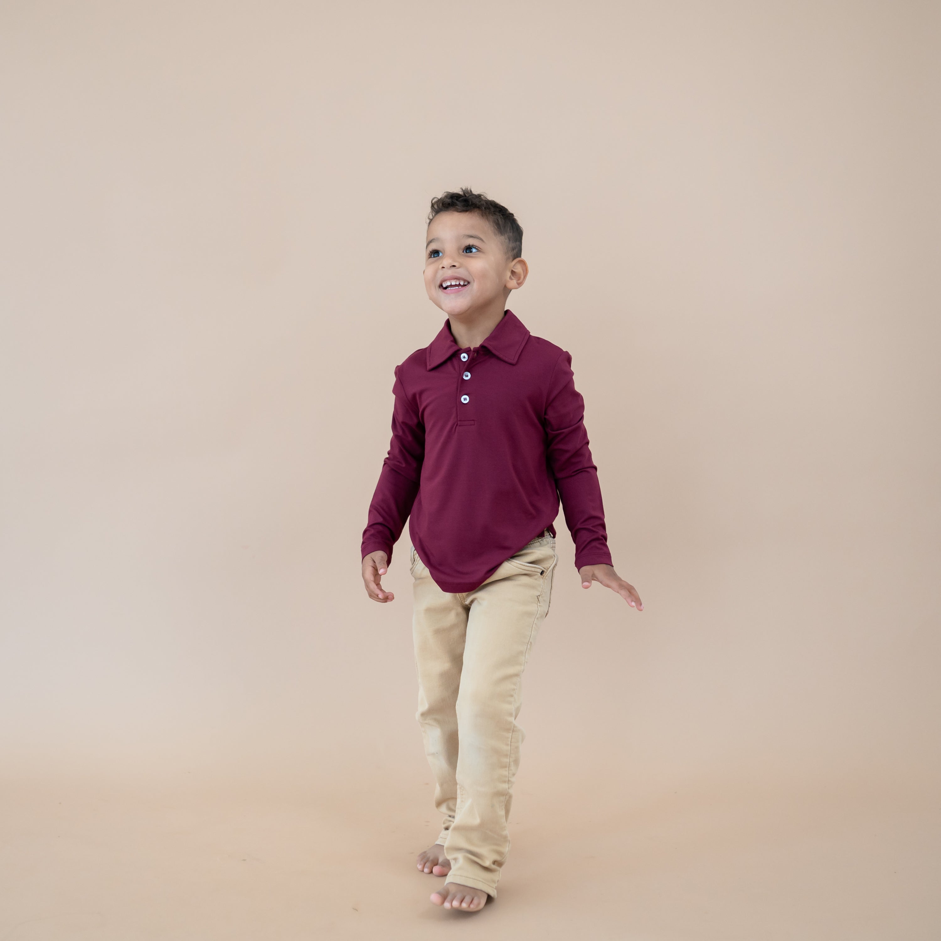 Young boy wearing the Toddler Long Sleeve Polo in Burgundy paired with khaki pants
