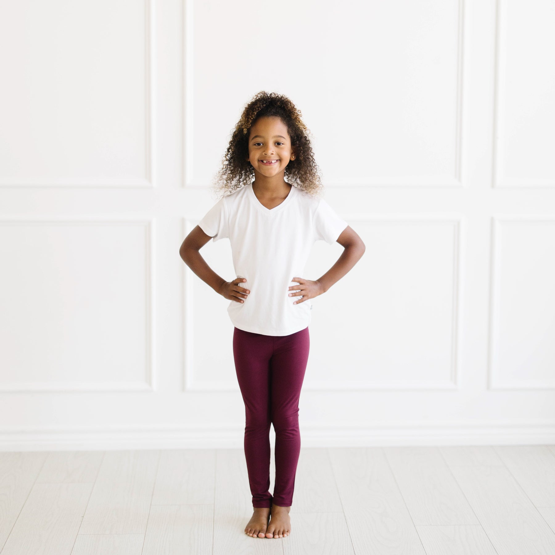 Smiling girl wearing the Toddler Leggings in Burgundy paired with a Snow V-neck