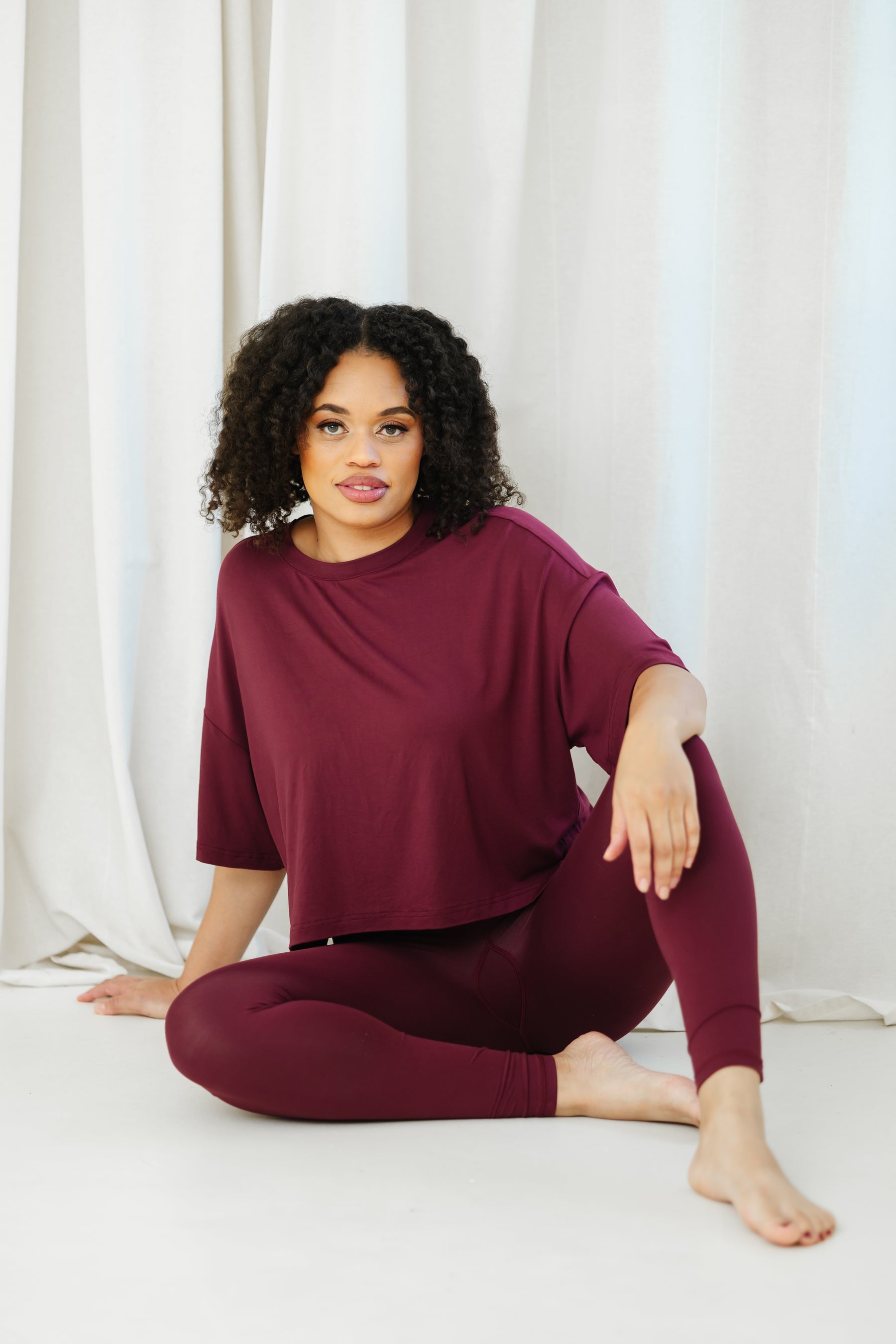 Female sitting on the floor wearing the Bamboo Flex Women’s Leggings in Burgundy with matching short sleeve tee