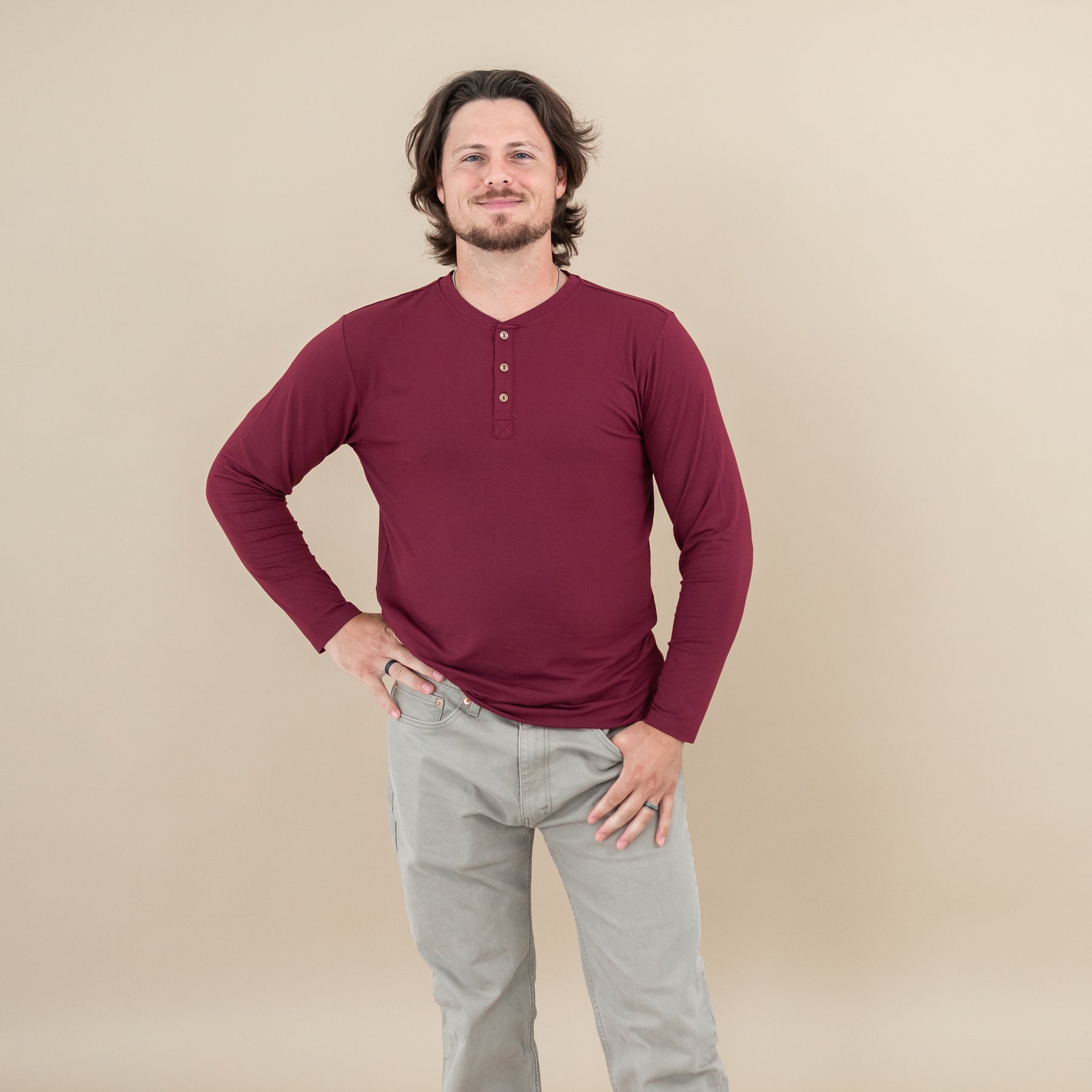 Male model wearing the Men's Long Sleeve Henley Top in Burgundy with one hand on hip
