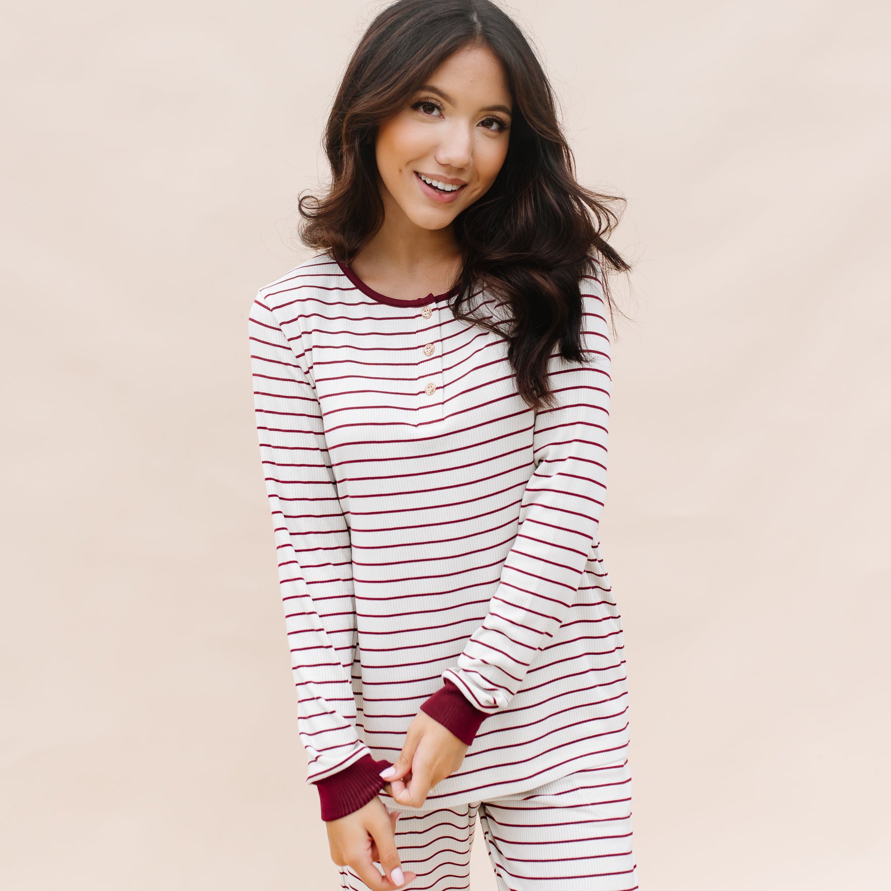 Smiling female wearing the Women’s Ribbed Henley Set in Burgundy Stripe standing in front of a light beige background