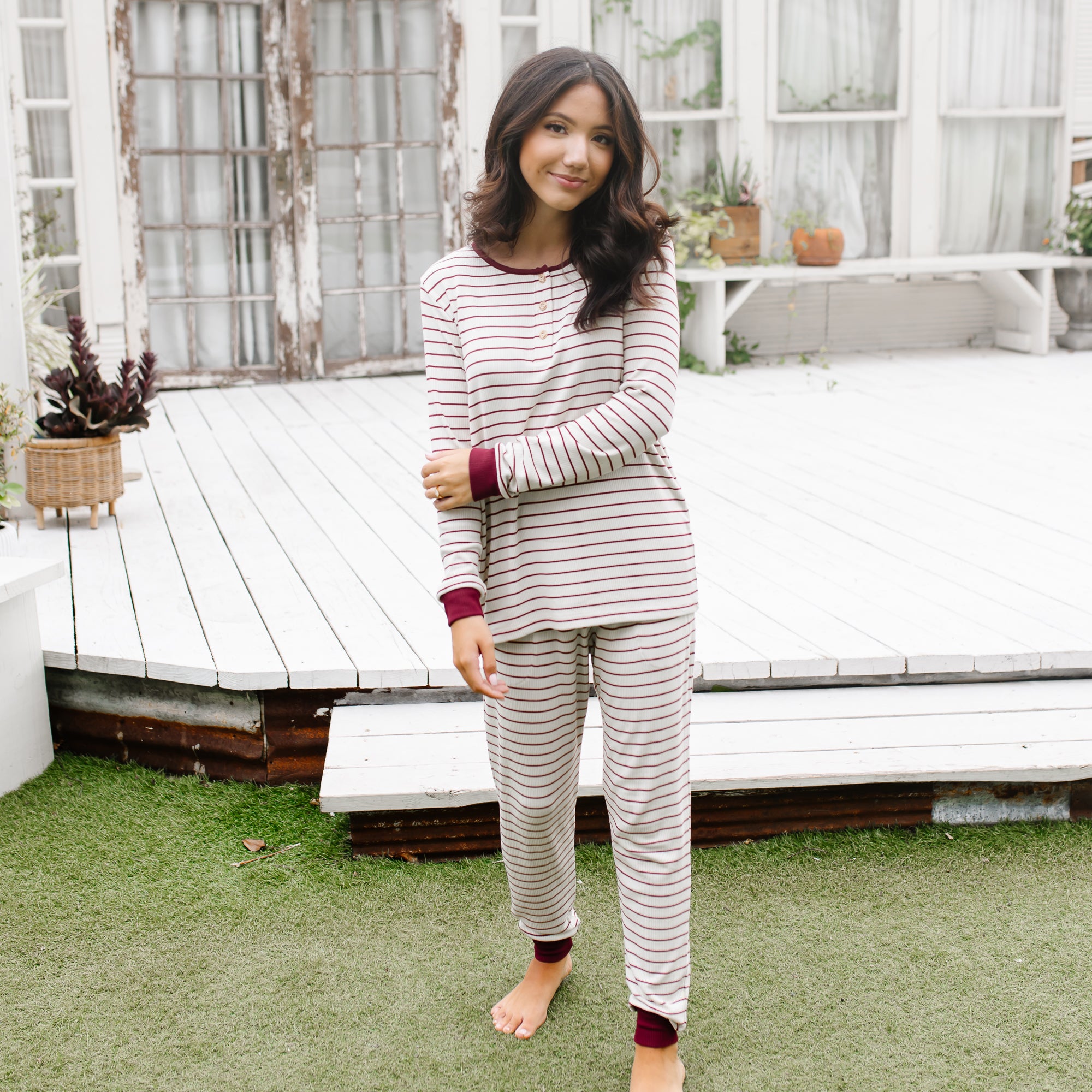 Female model walking outside in front of a white patio wearing the Women’s Ribbed Henley Set in Burgundy Stripe