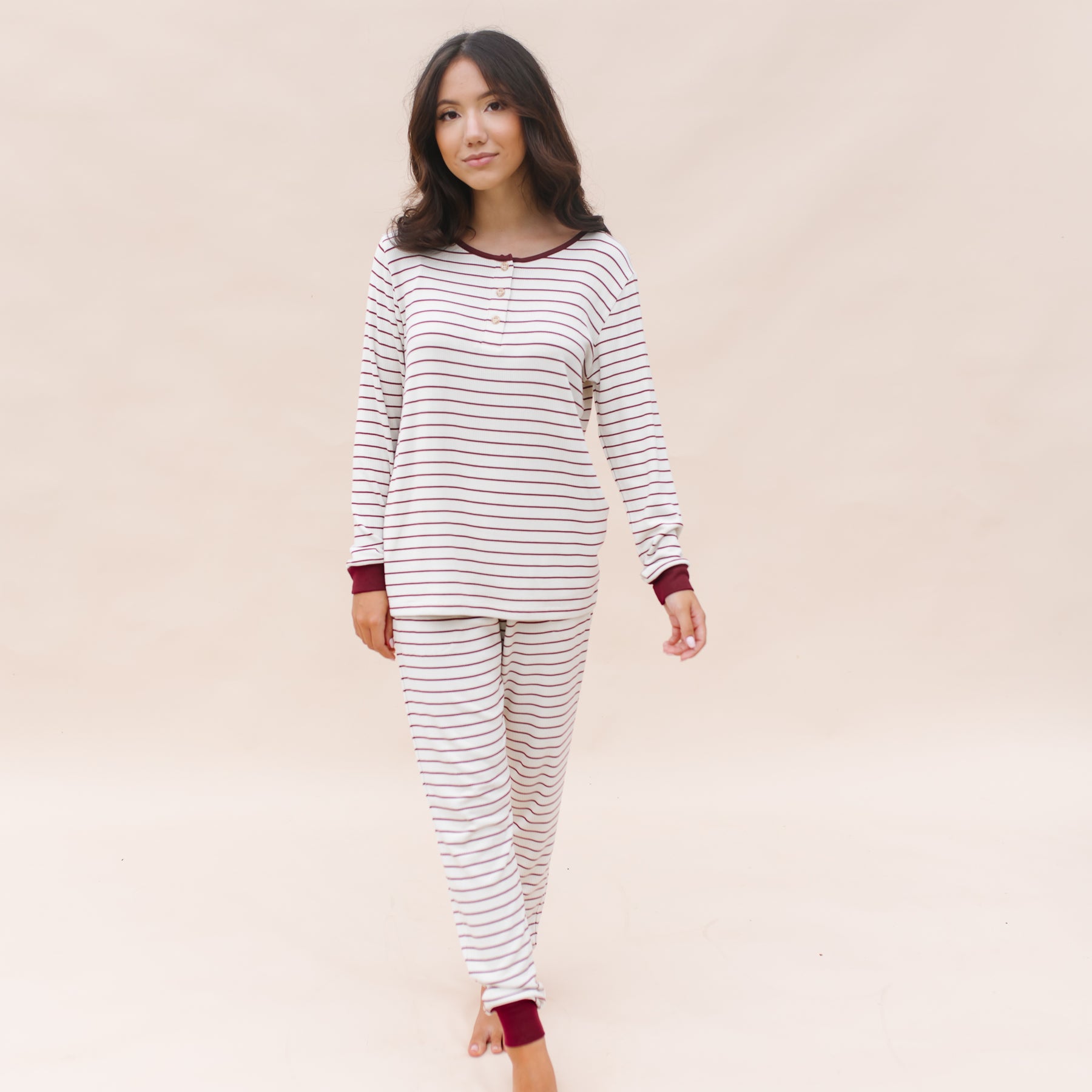 Female walking wearing the Women’s Ribbed Henley Set in Burgundy Stripe in front of a light beighe background