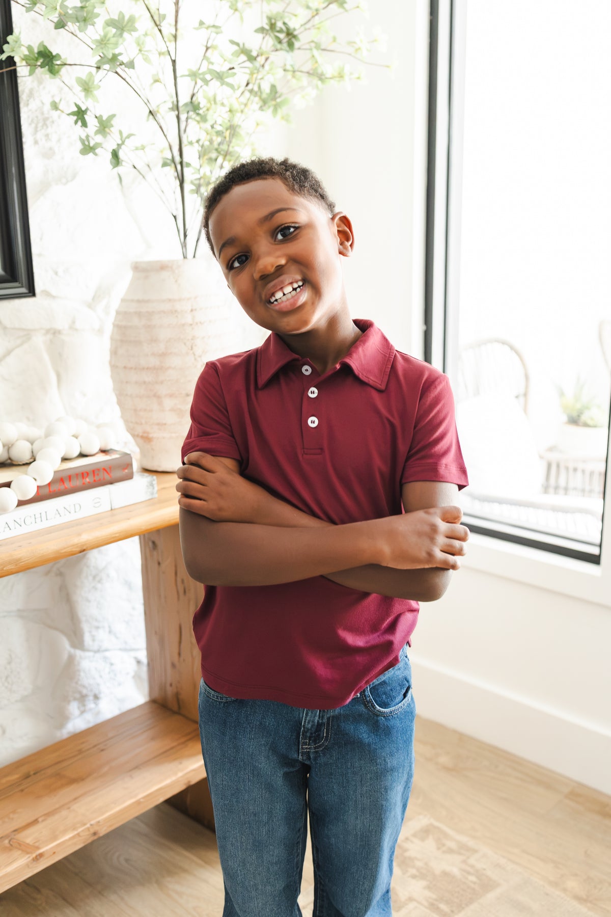 Boy wearing Toddler Short Sleeve Polo in Burgundy standing with folded hands on blue jeans