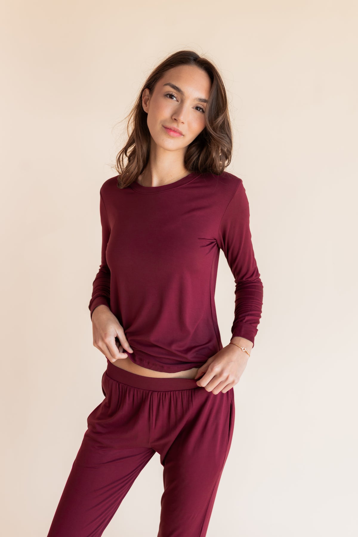 Model posing Women's Jogger Pajama Set in Burgundy on a beige background
