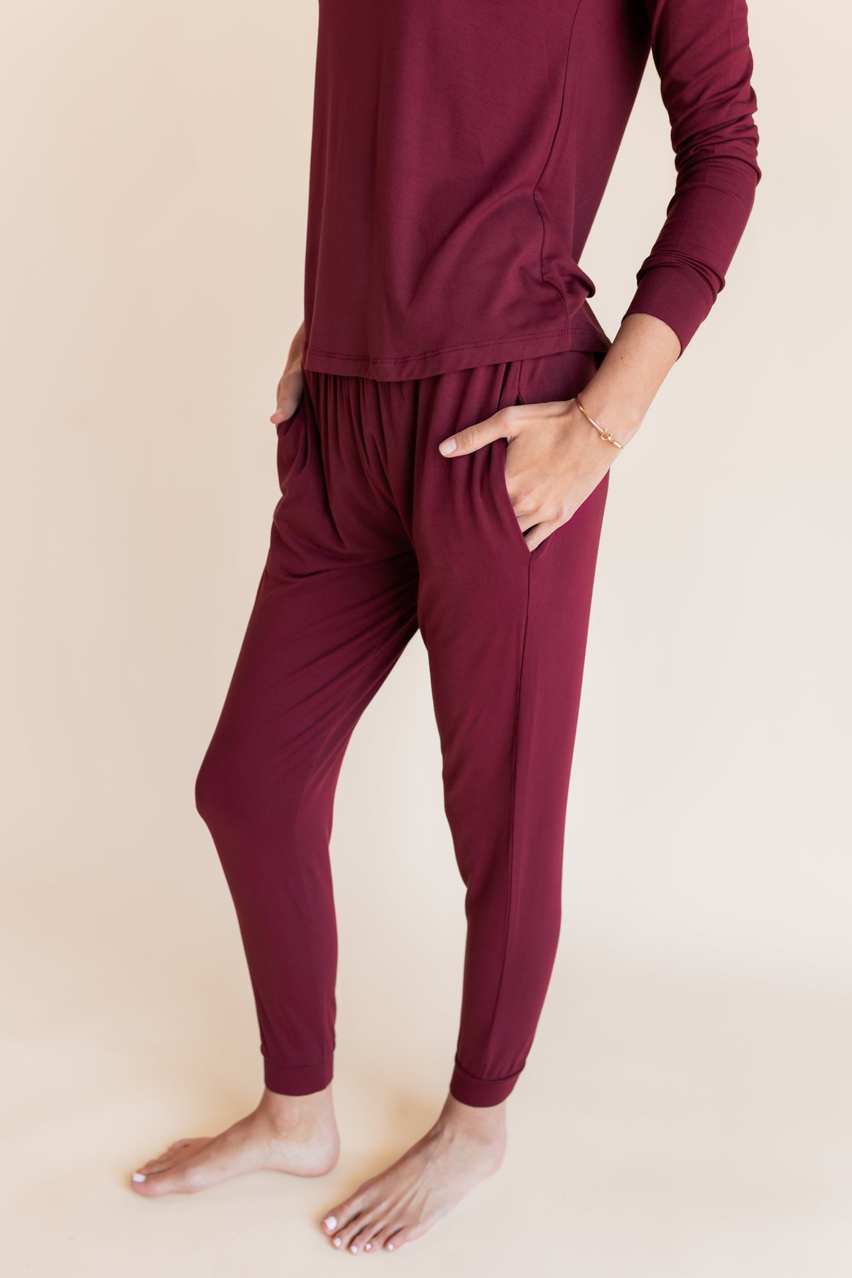 Model showcasing pockets on Women's Jogger Pajama Set in Burgundy on a beige background