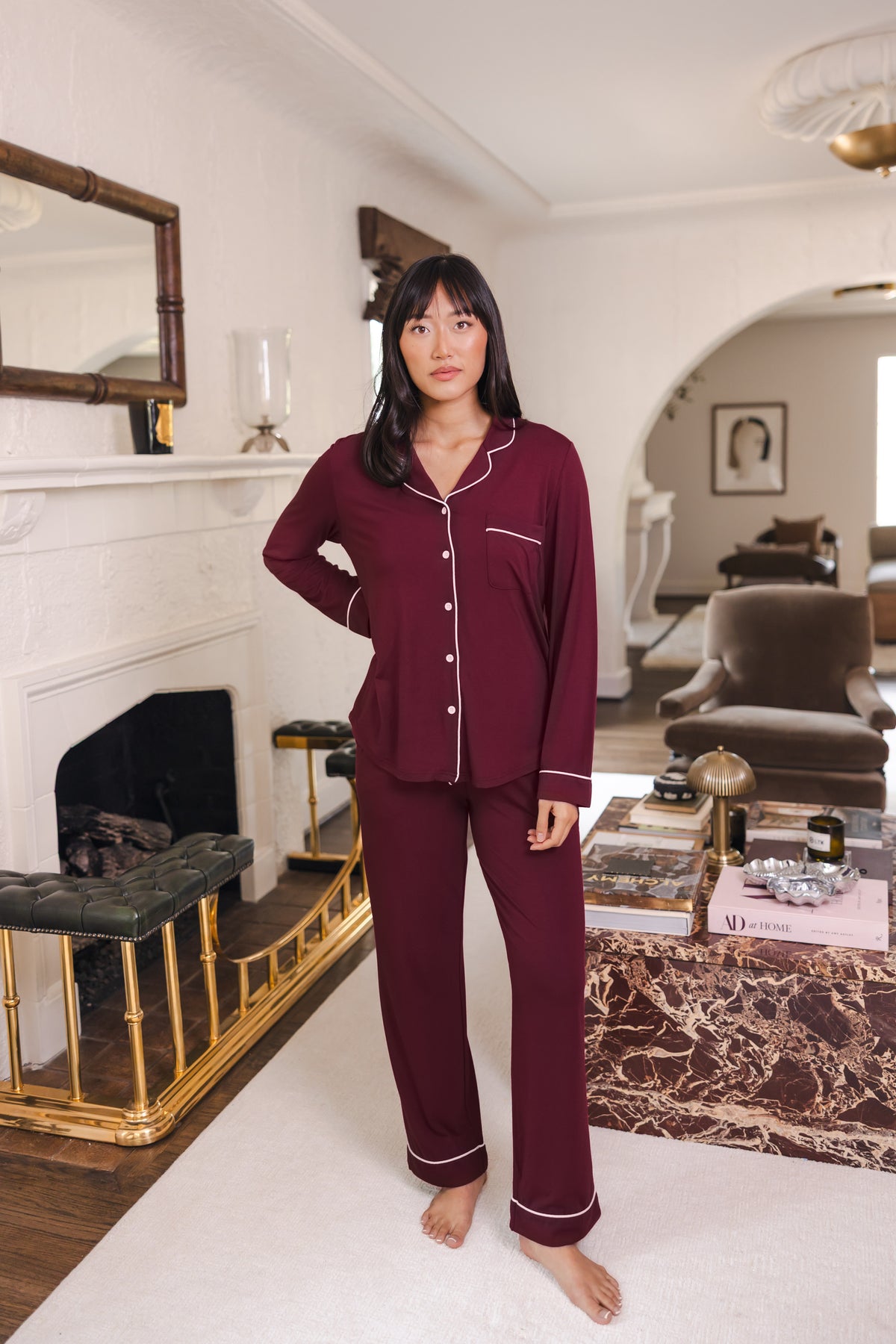 Modal standing in a living room wearing Long-Sleeved Women's Pajama Set in Burgundy with Burgundy Trim