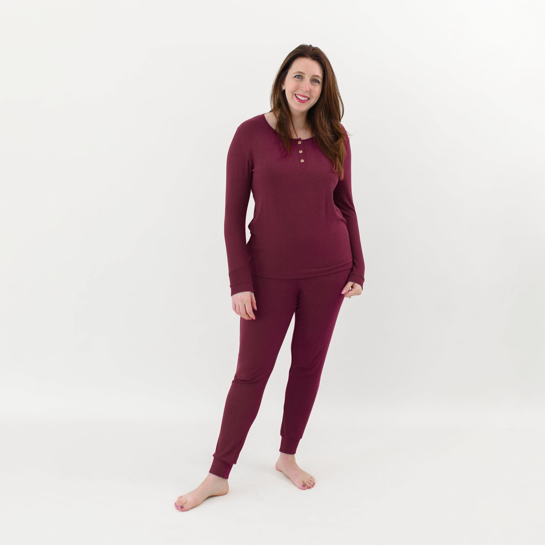 Smiling female model wearing the Women’s Ribbed Henley Set in Burgundy in front of a light colored back drop