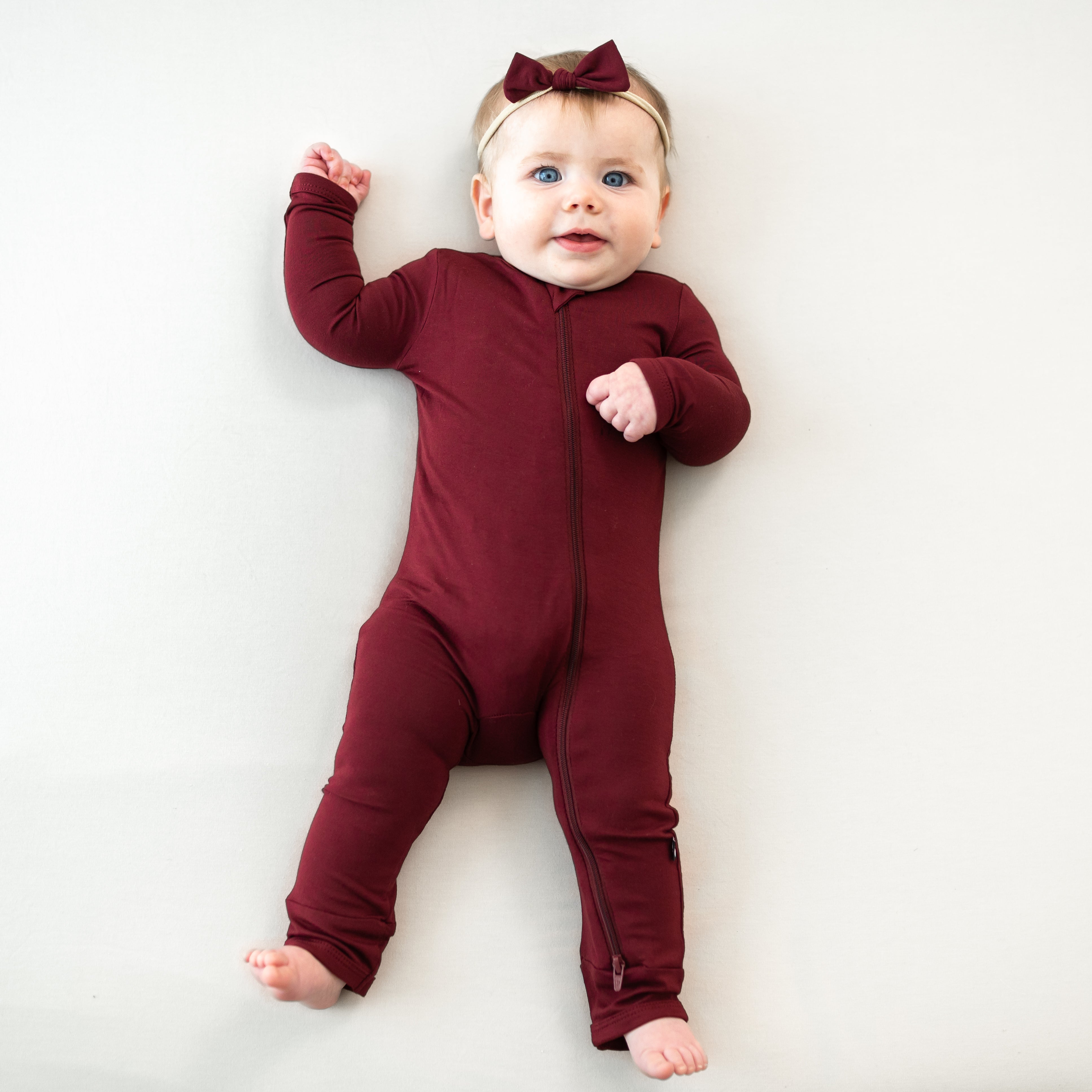 Infant wearing the Tiny Nylon Bow in Burgundy with matching zippered romper