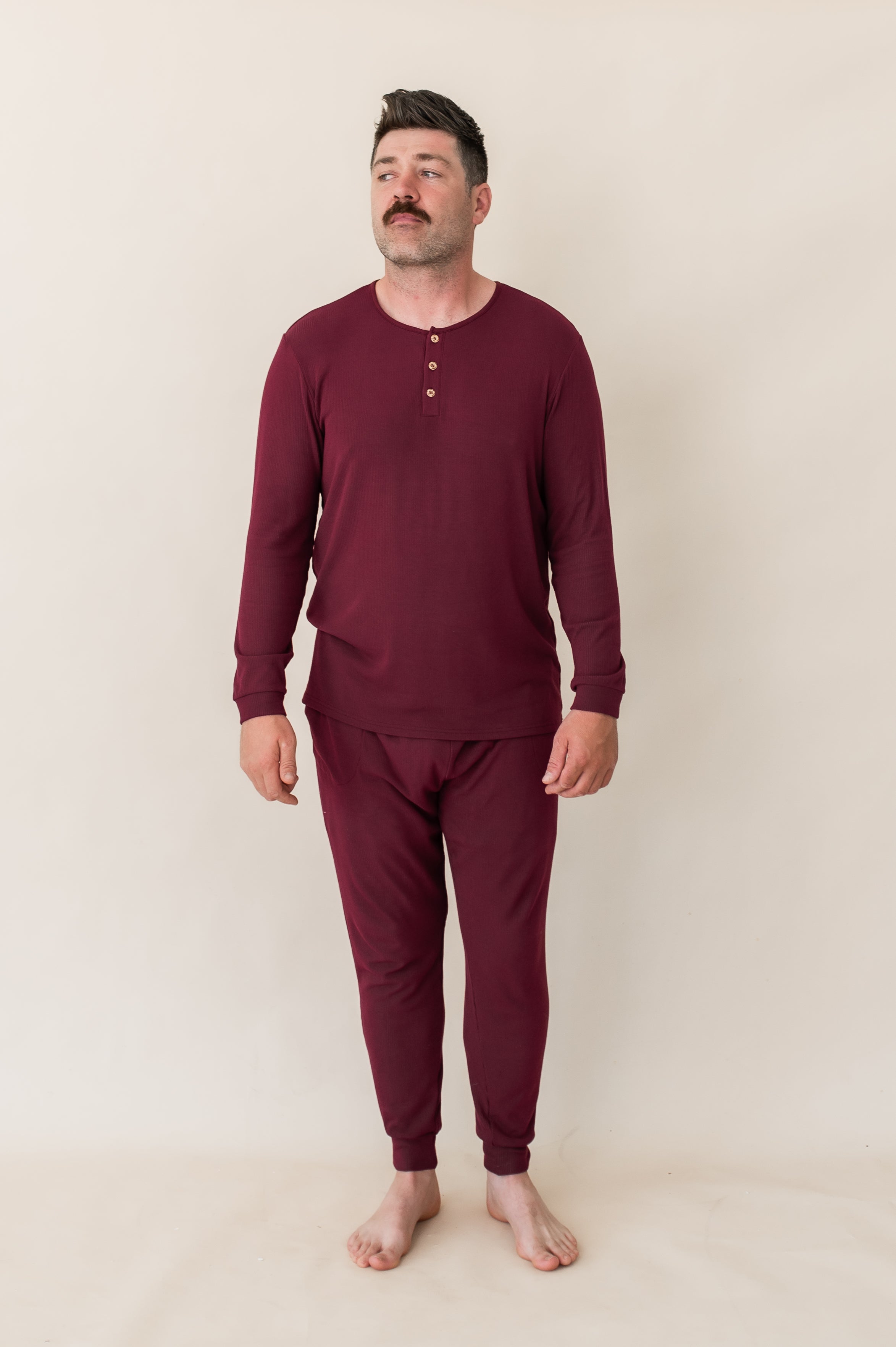 Male model looking off to the side wearing the Men's Ribbed Henley Set in Burgundy
