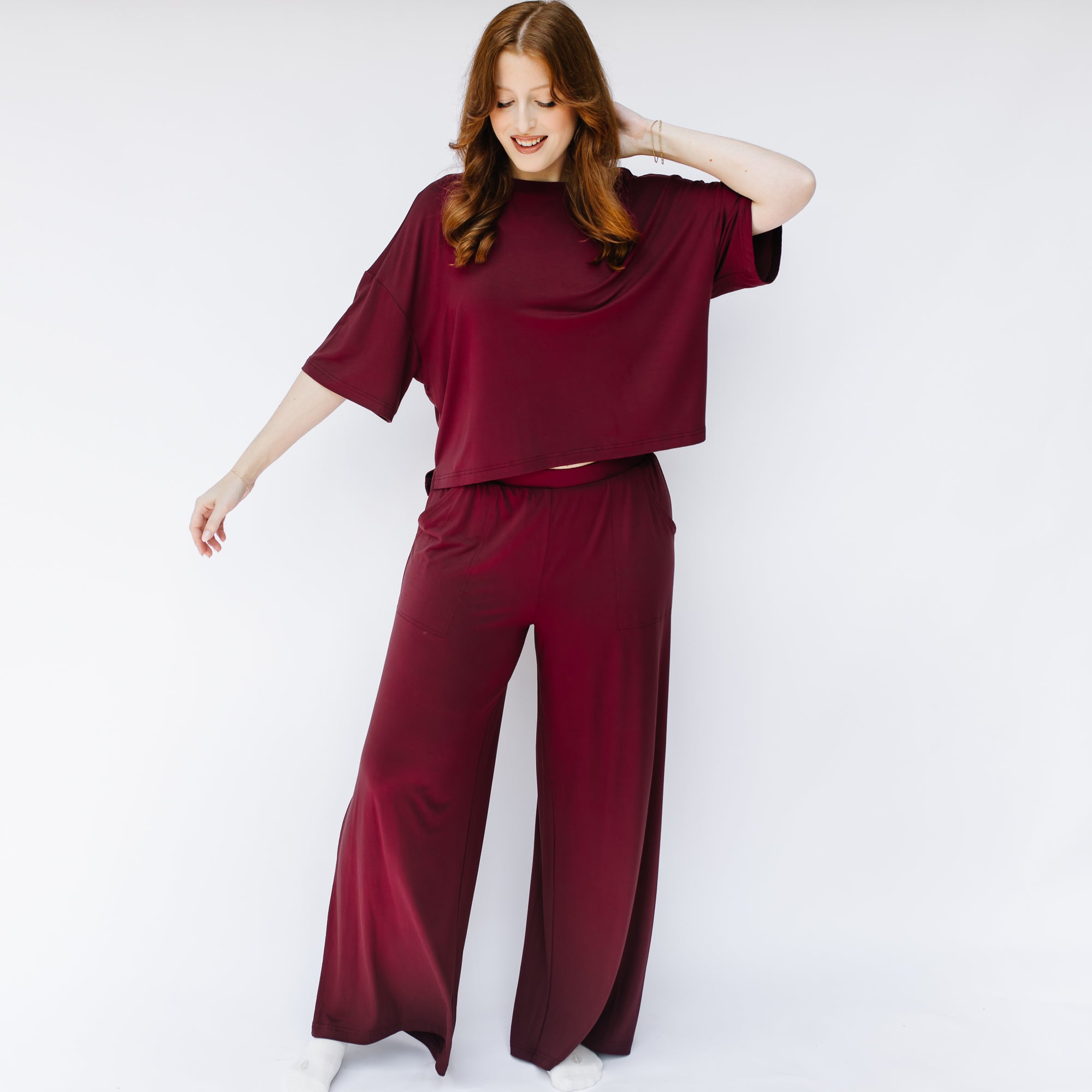Female model standing in front of a white background wearing the Women's Wide Leg Pant in Burgundy and matching short sleeve tee