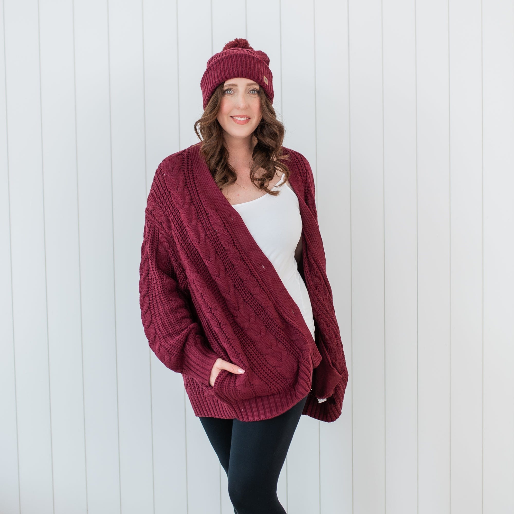 Female walking with hands in the pocket of the Cable Knit Adult Cardigan in Burgundy