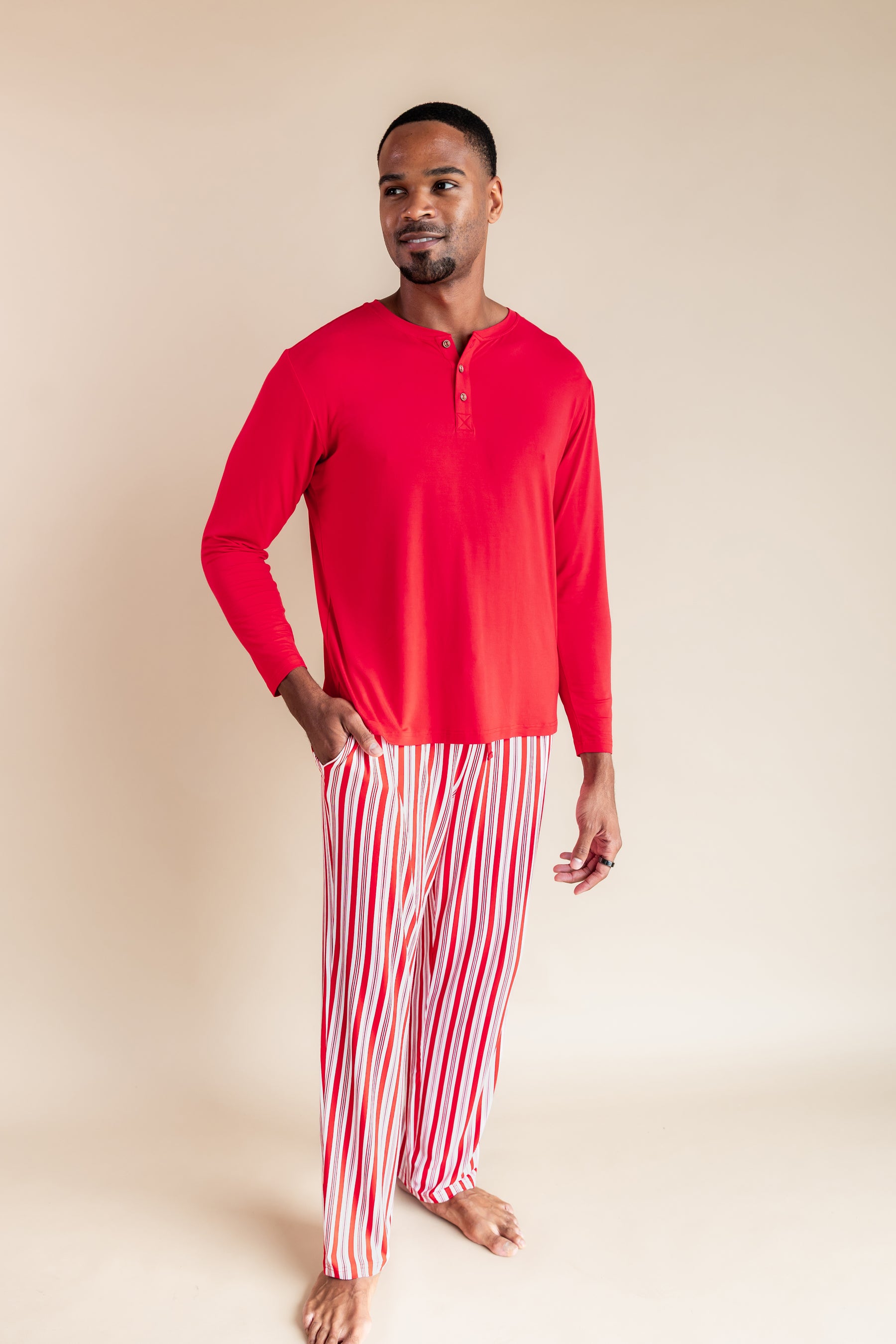 Modal wearing Men's Lounge Pants in red and white Peppermint Stripes print under red T-shir on a beige background