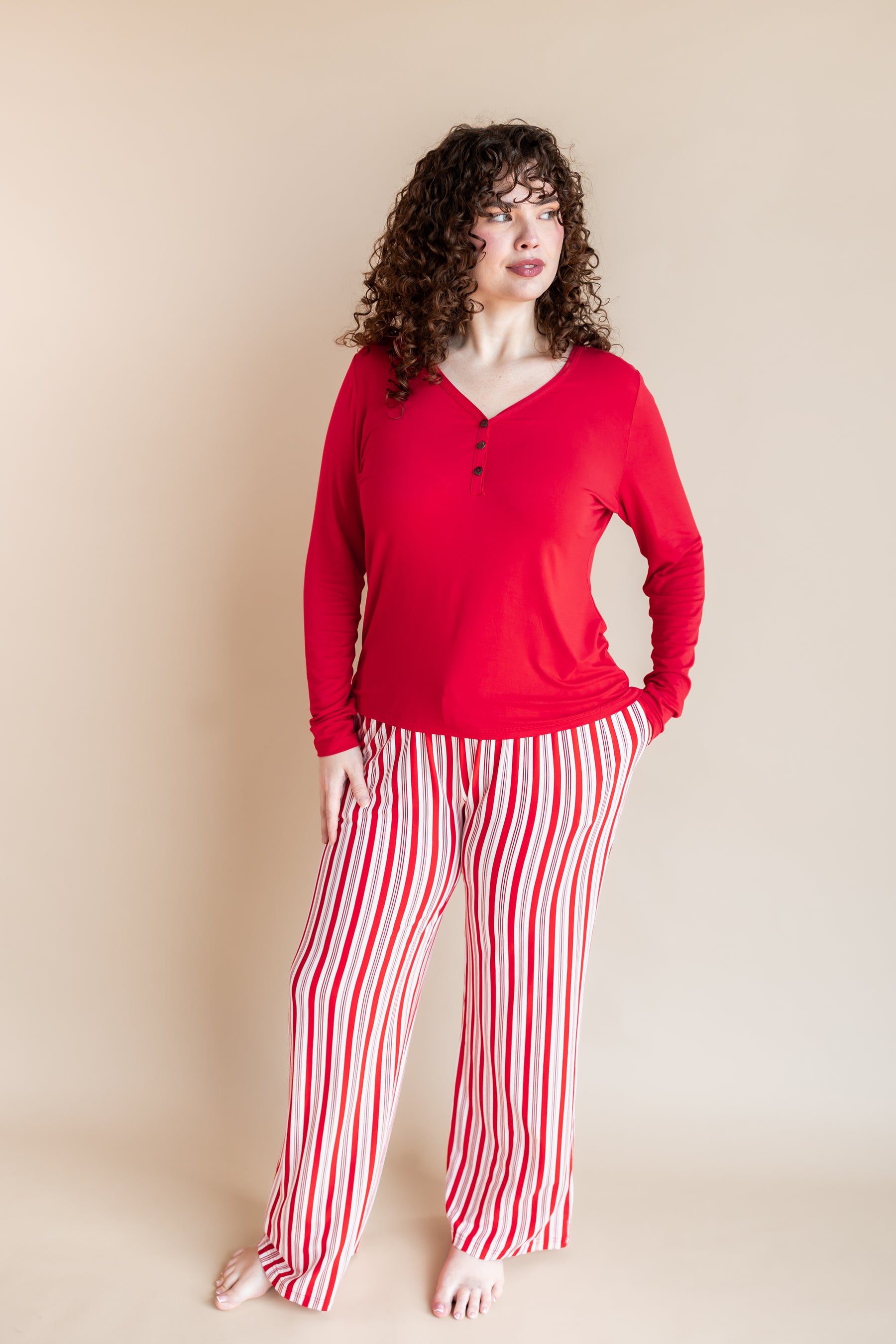Modal wearing Women's Lounge Pants in red and white Peppermint Stripes print under a red T-shirt on a beige background
