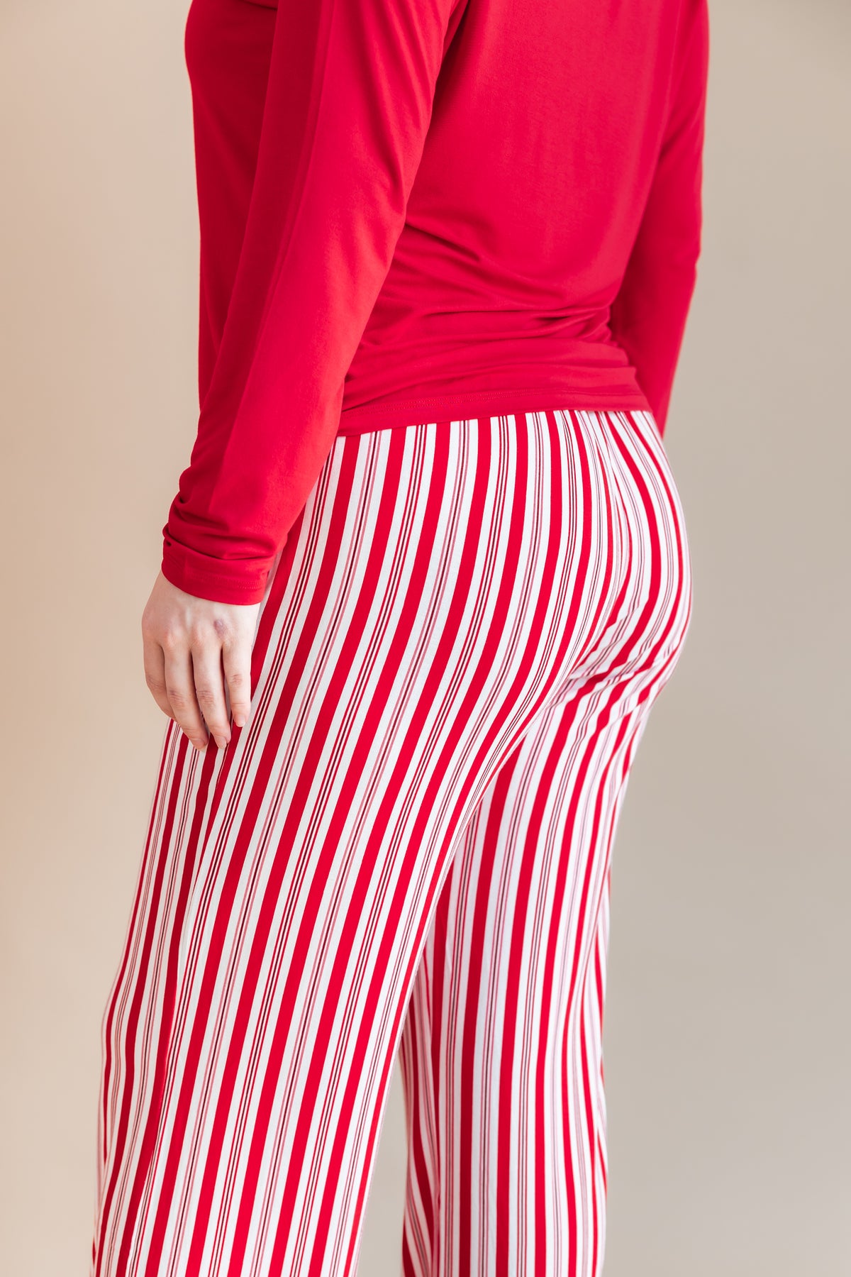 Modal showcasing the back side of Women's Lounge Pants in red and white Peppermint Stripes print under a red T-shirt on a beige background