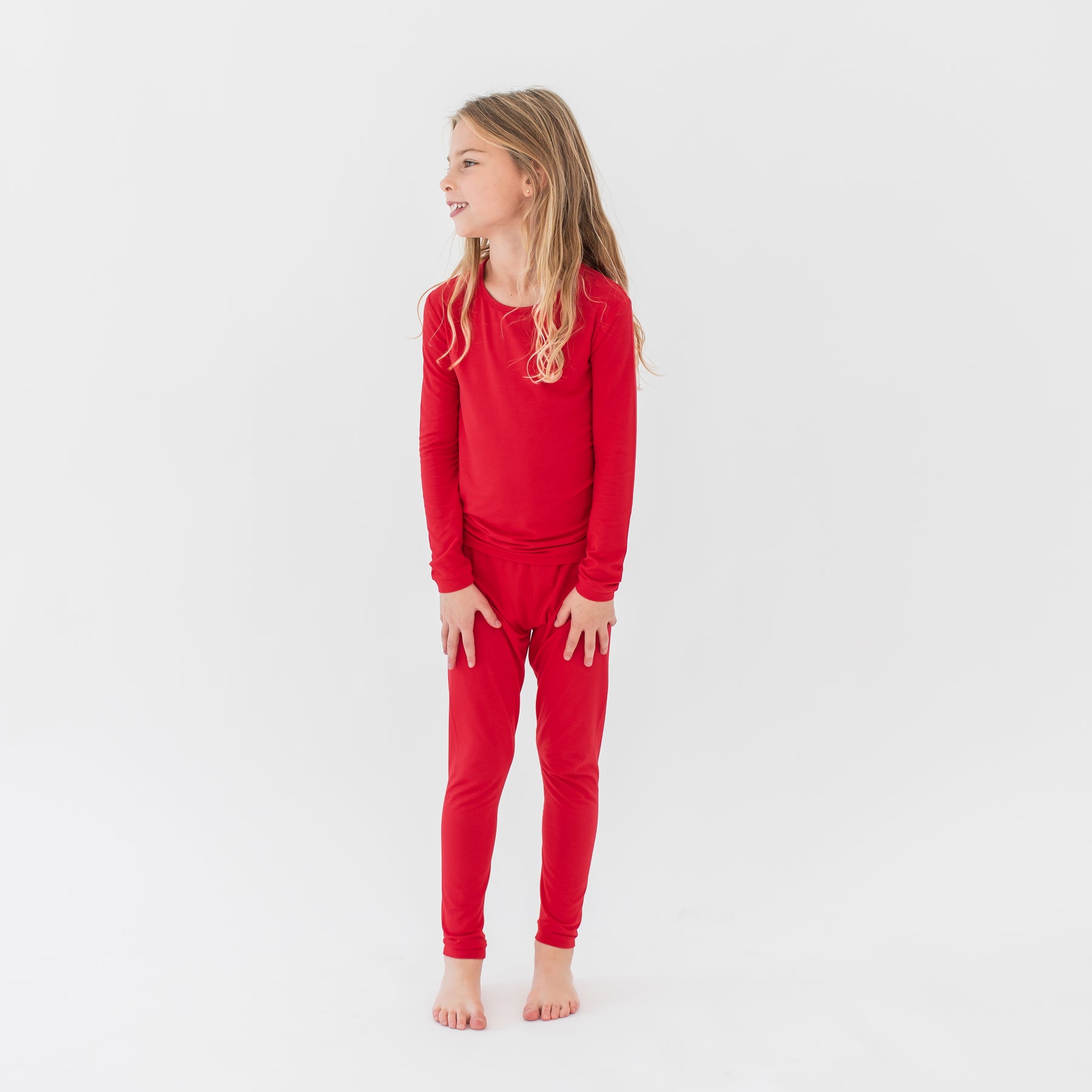 Young girl wearing the Long Sleeve Pajamas in Cardinal in front of a white background
