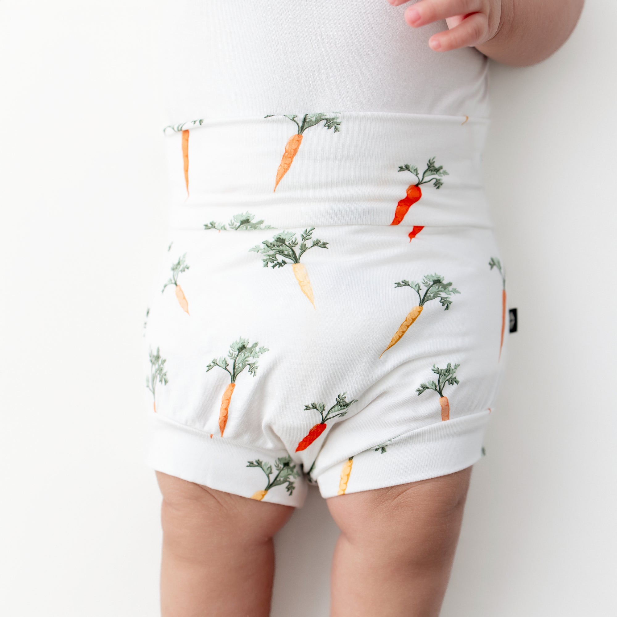 Close up of the Bummies in Carrot shown on an infant model laying on a white surface