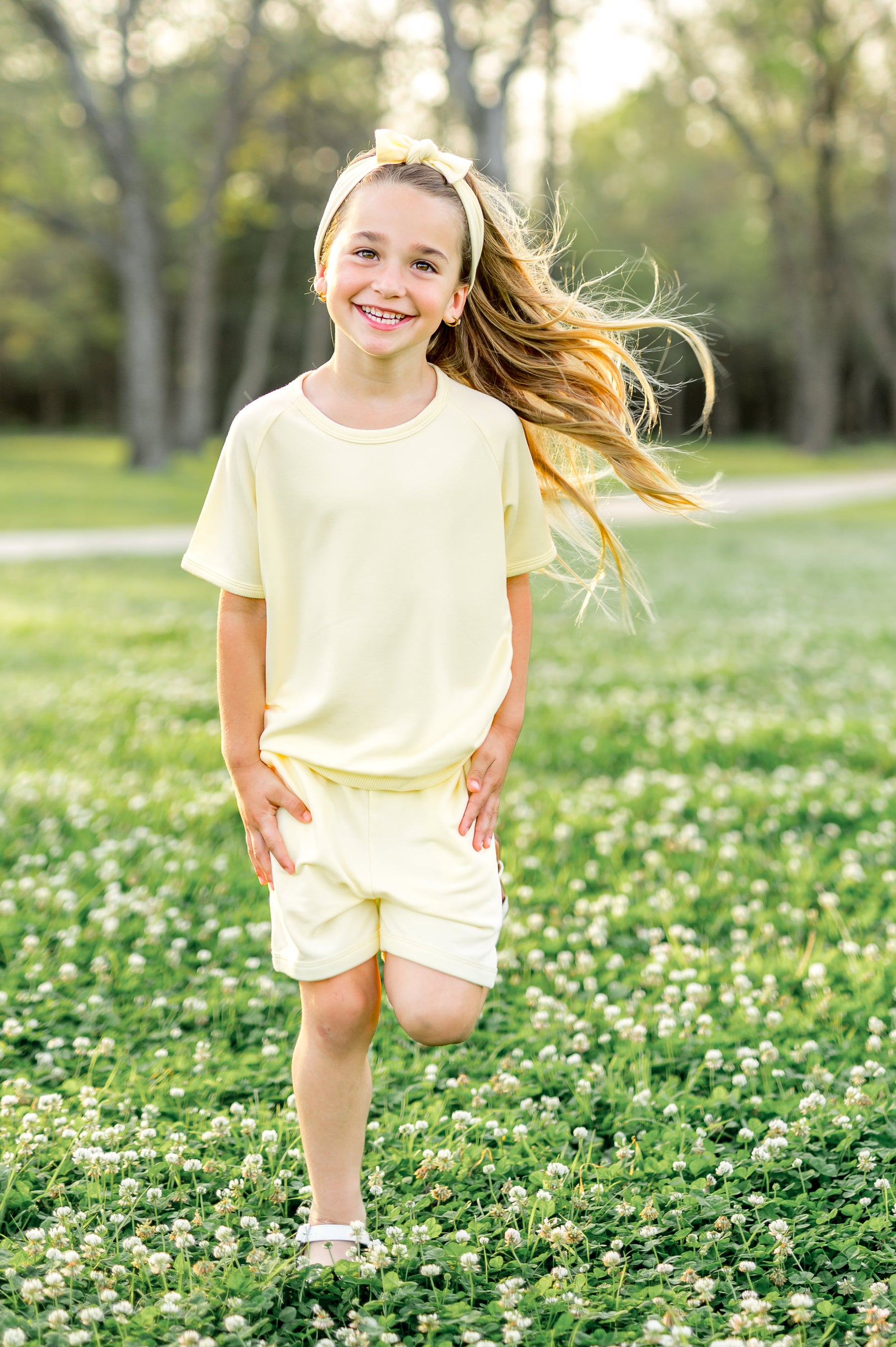 Young girl walking through the grass field wearing the Short Sleeve Jogger Set in Chamomile