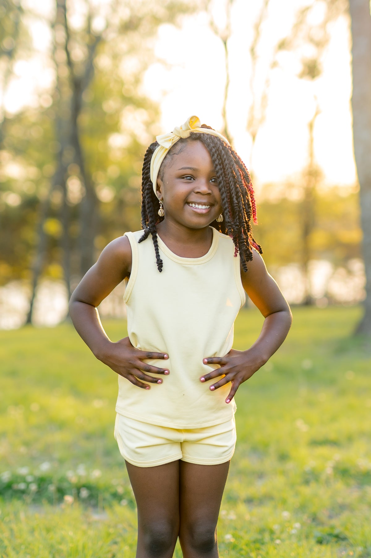 Young girl posing wearing the Tank Jogger Set in Chamomile standing in front of a sunset standing in a field