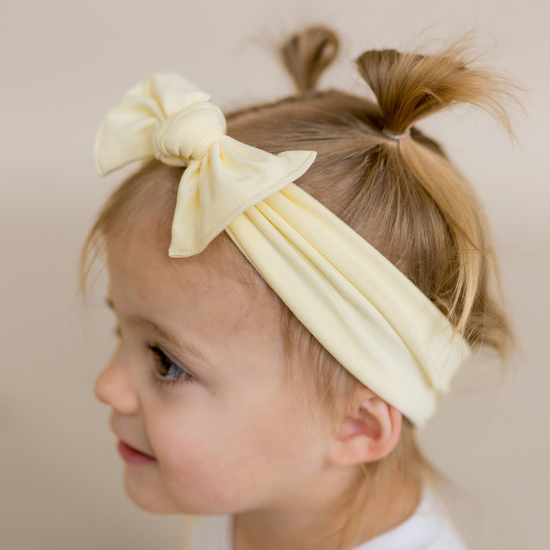 Young girl wearing the Knotted Bow Headband in Chamomile