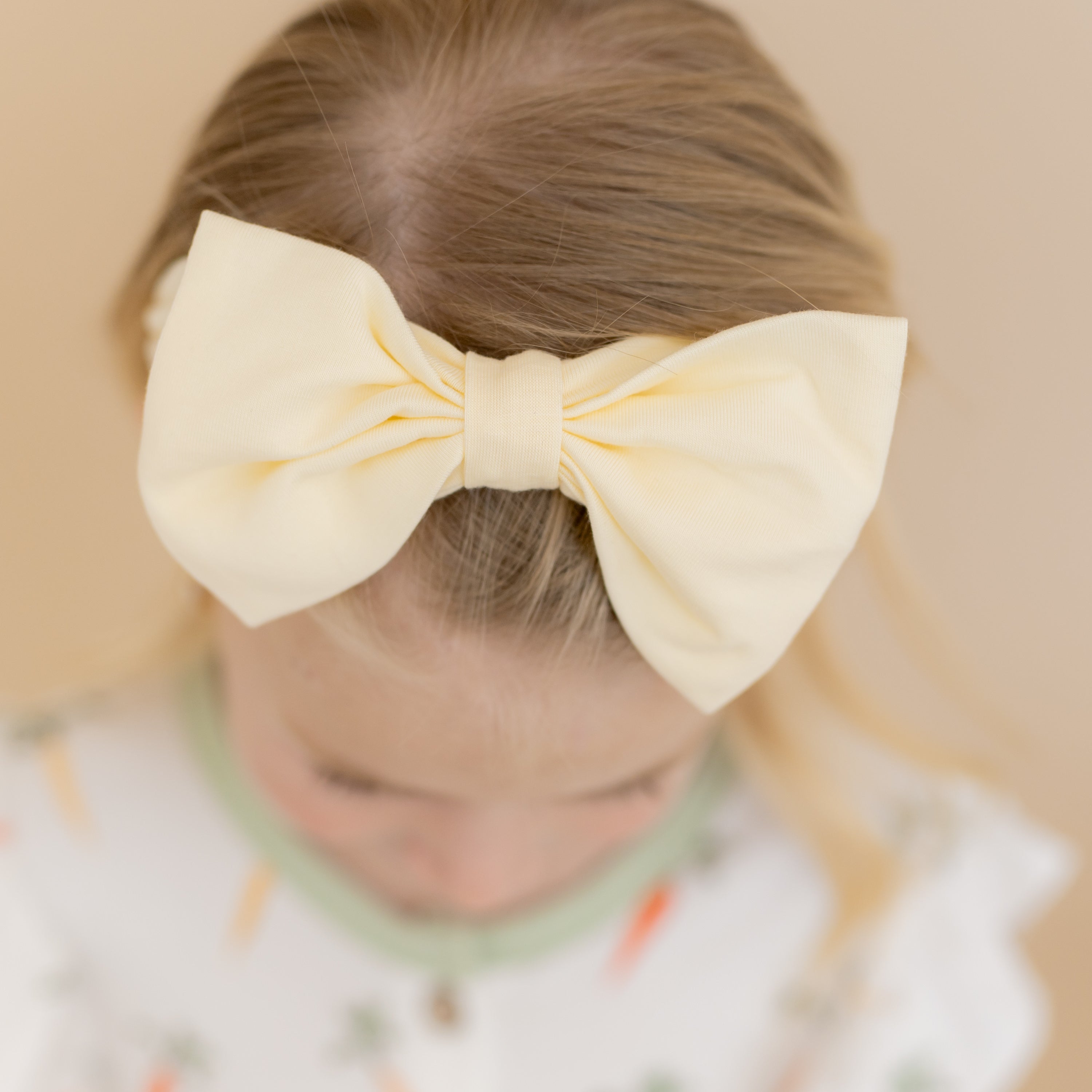 Close up of the Bow Headband in Chamomile shown on a young girl