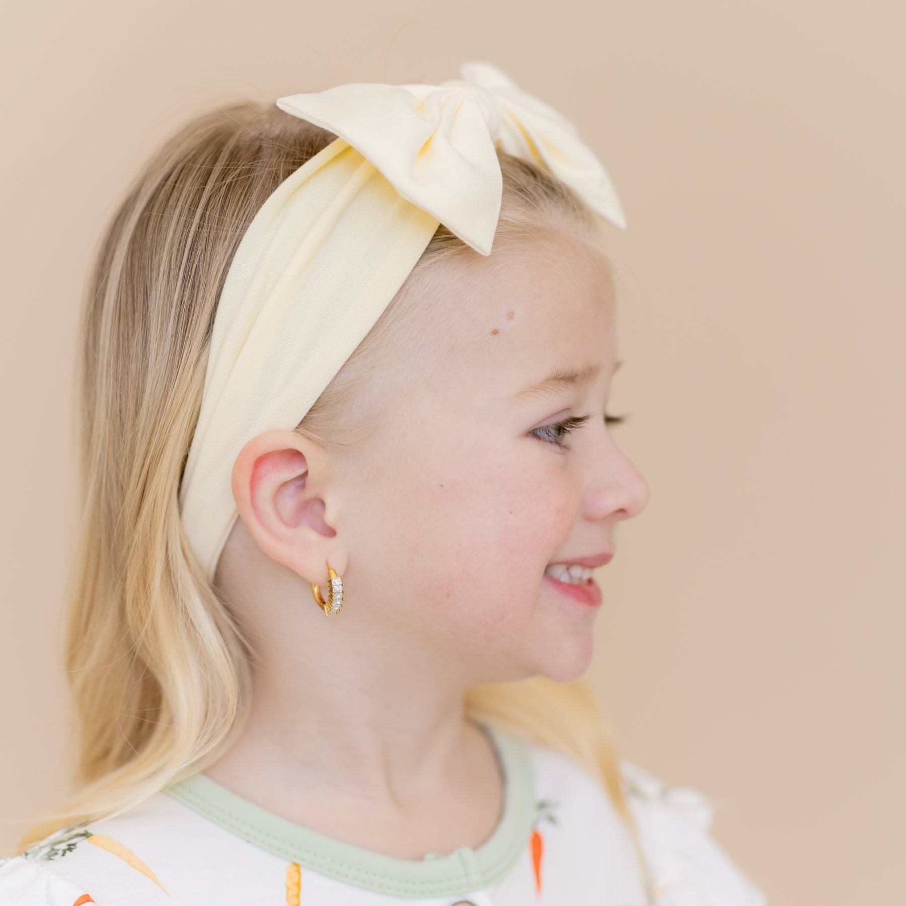 Side view of the Bow Headband in Chamomile shown on a young girl