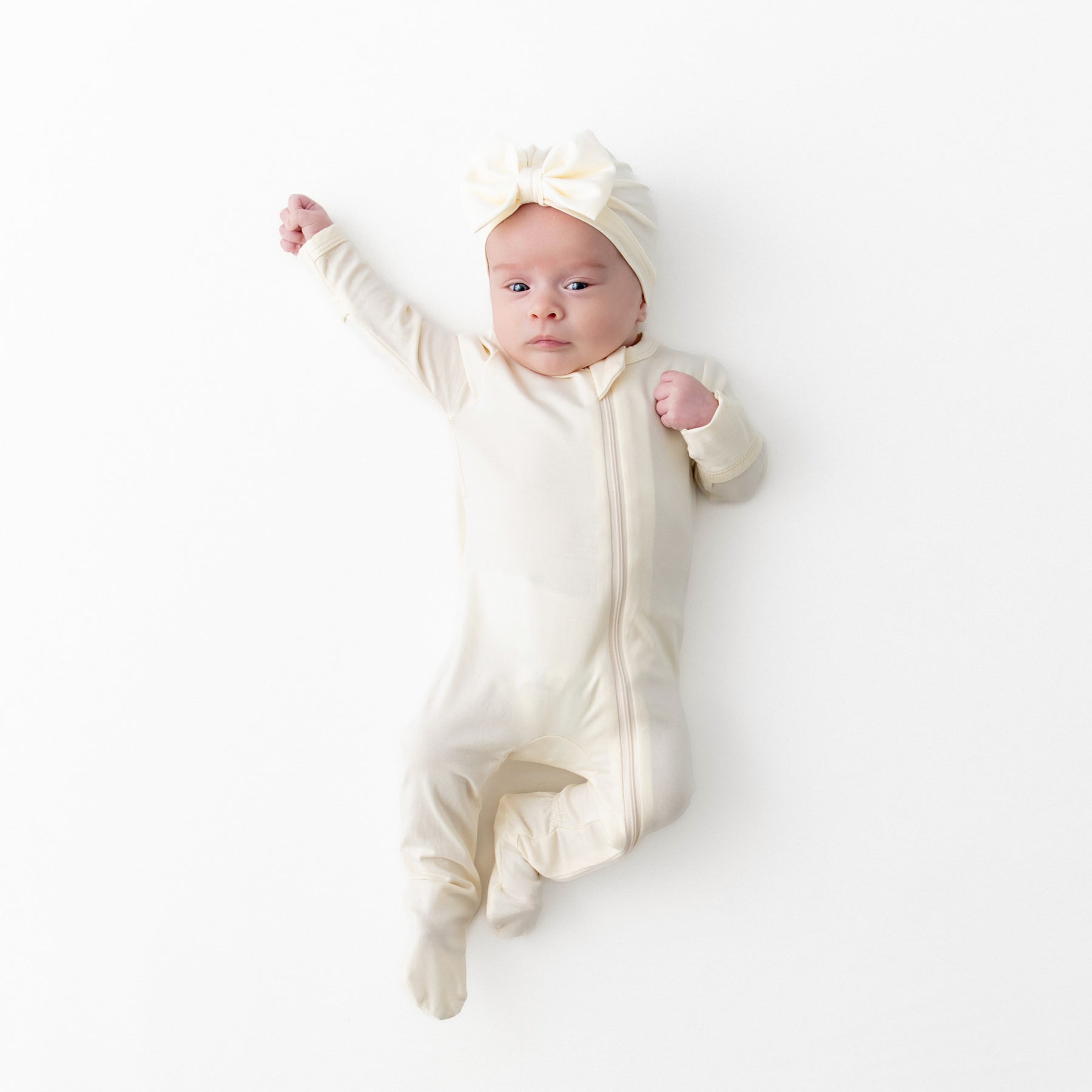 Infant wearing the Zippered Footie in Chamomile with matching bow headwrap