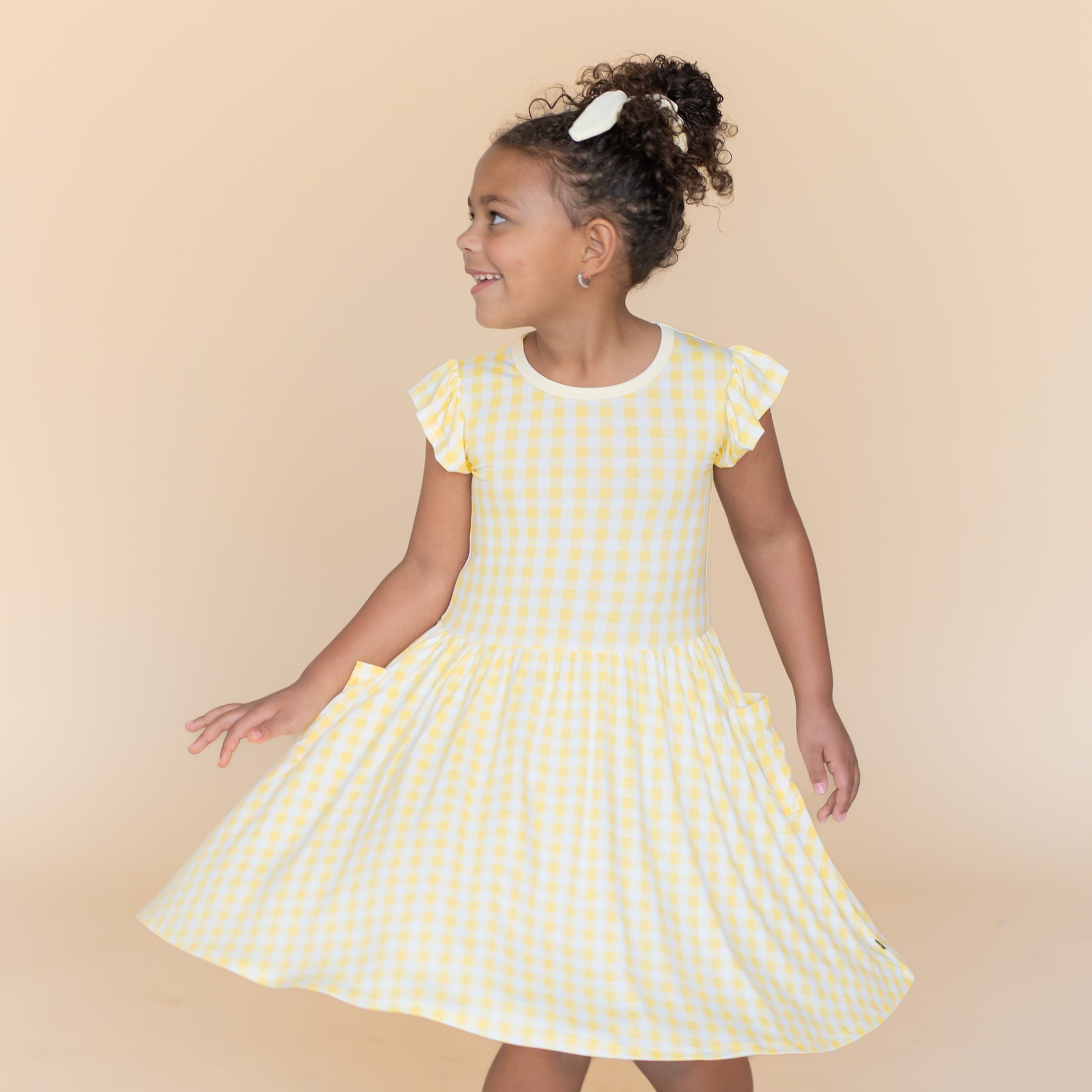 Young girl twirling wearing the Pocket Dress in Gingham Chamomile