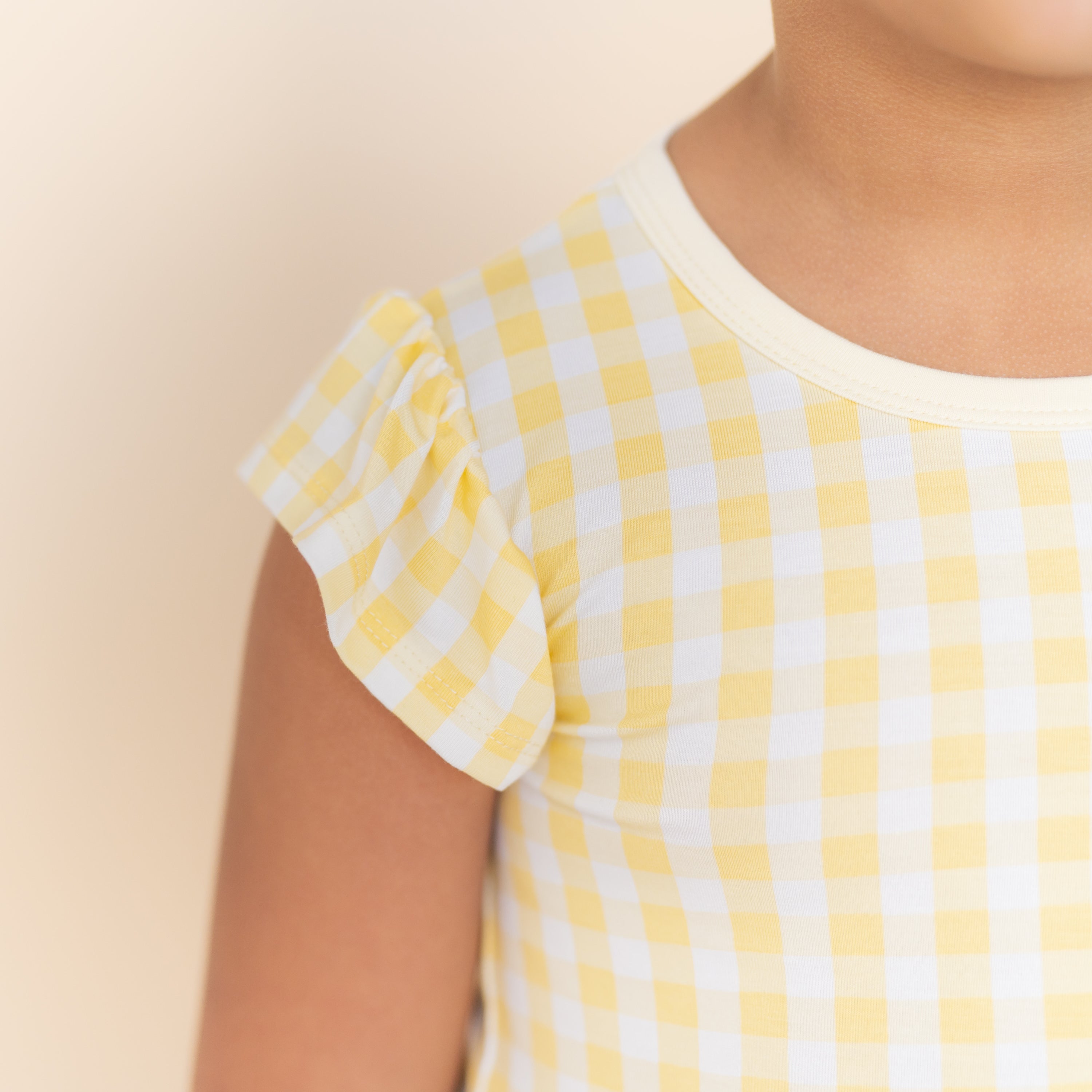 Close up of the flutter sleeve and solid light yellow neck trim on the Pocket Dress in Gingham Chamomile