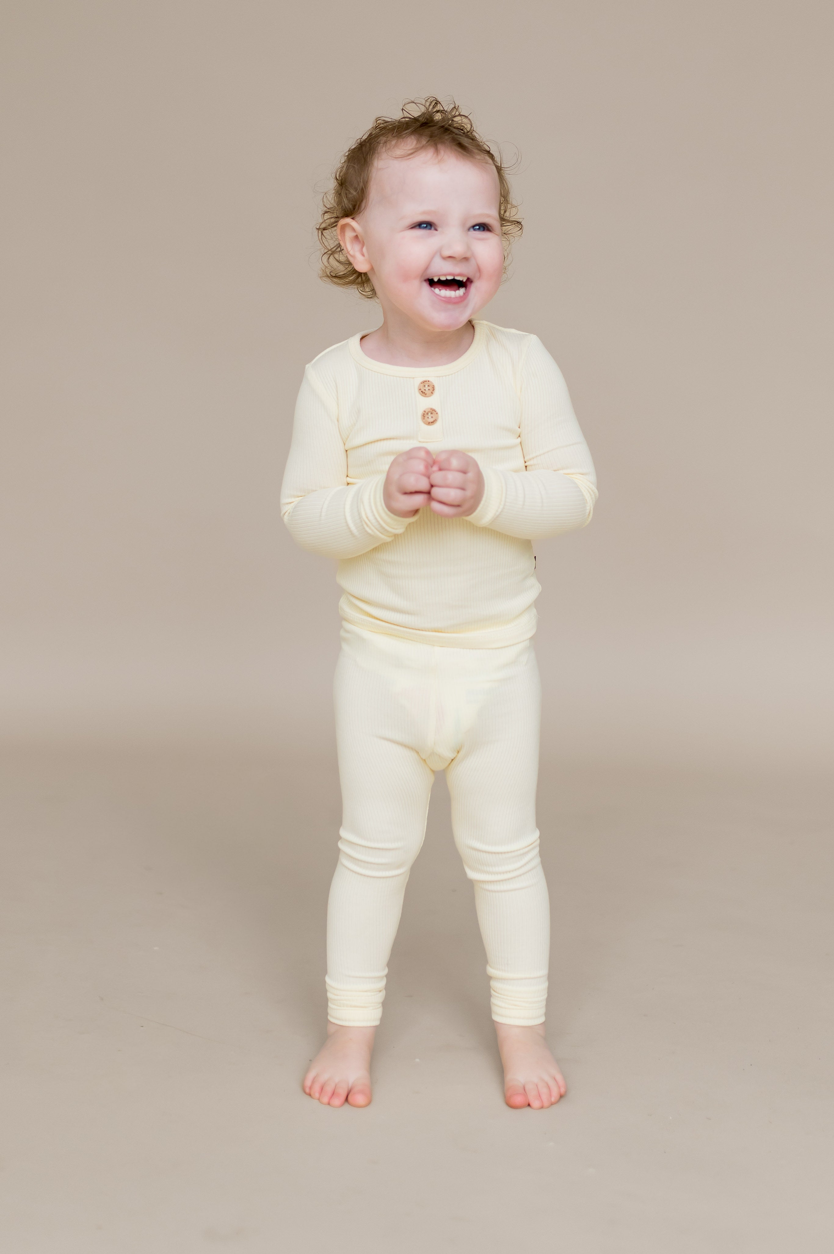 Smiling child standing wearing the Ribbed Henley Set in Chamomile