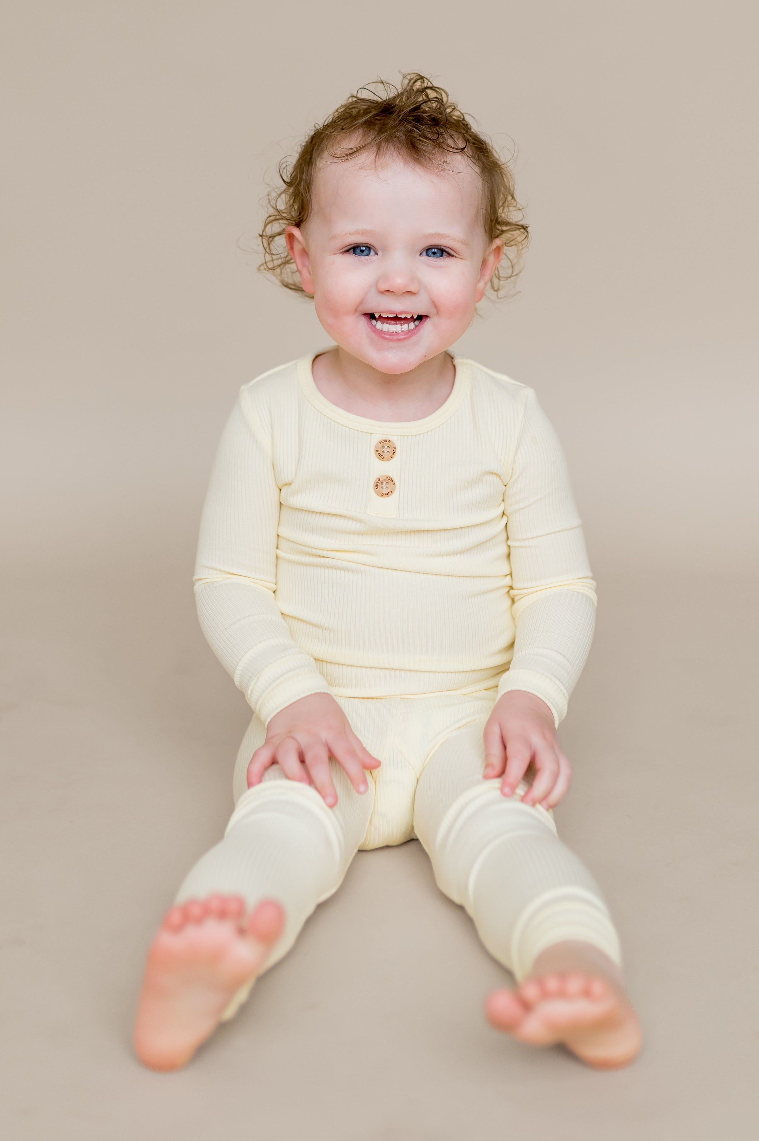 Young child sitting on the ground wearing the Ribbed Henley Set in Chamomile