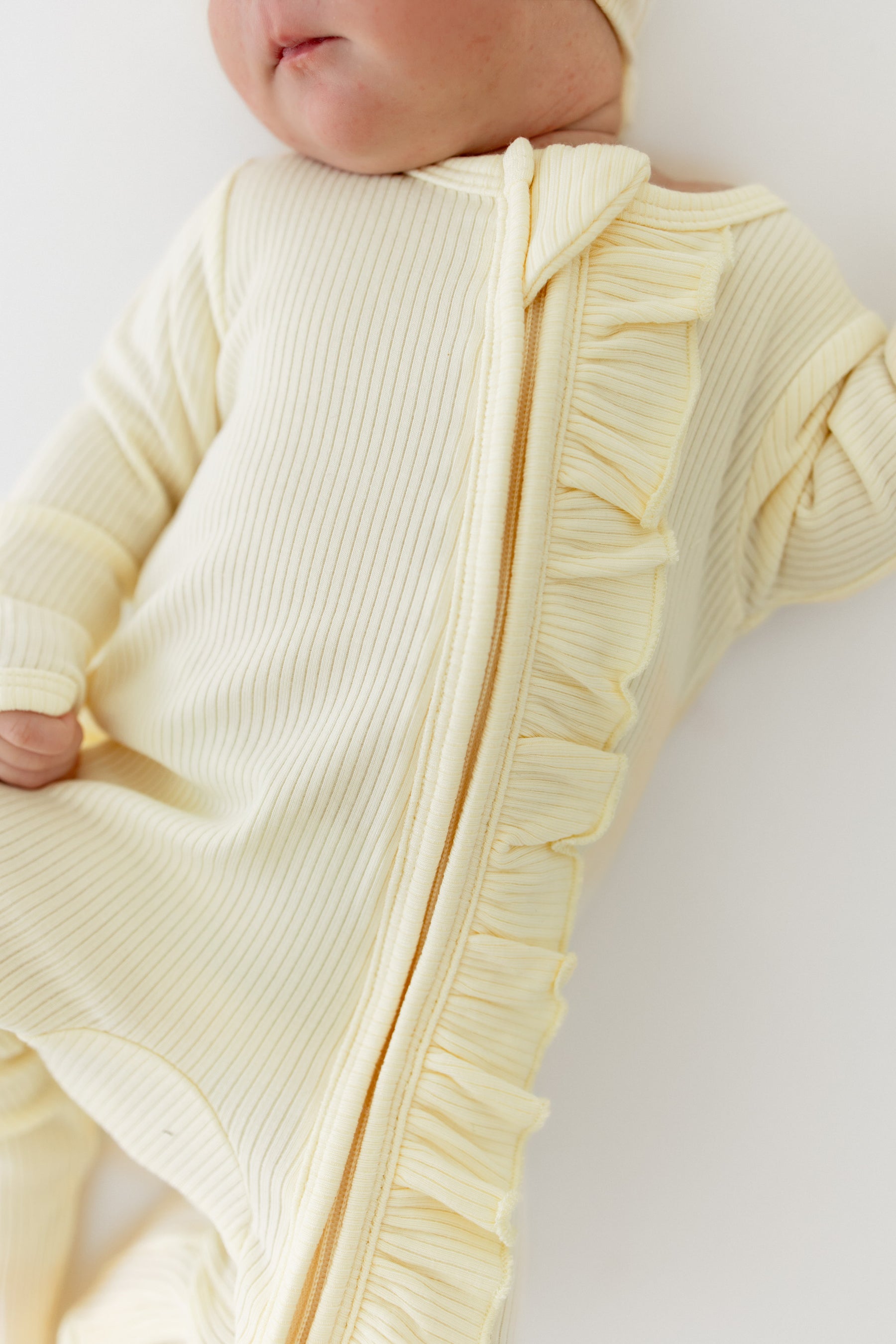 Close up of the zipper closure and ruffle fabric on the Ribbed Ruffle Zipper Footie in Chamomile