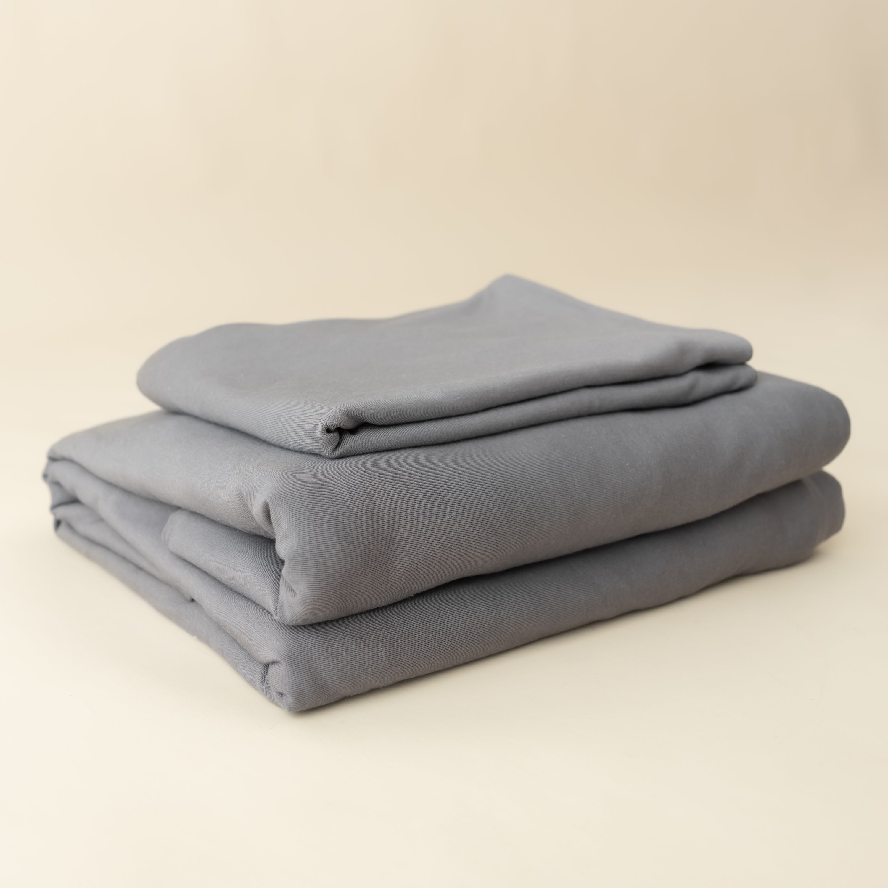 charcoal fitted sheet and pillow cases neatly folded and stacked on top of each other in an angle