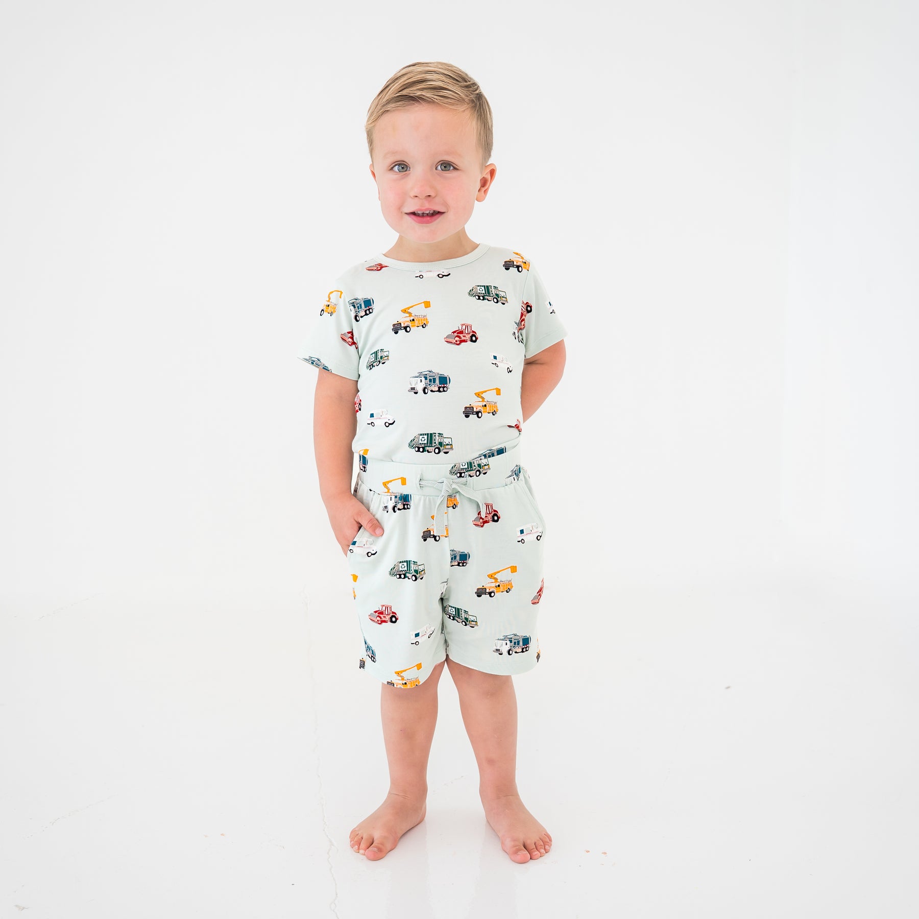 Young boy modeling the Drawstring Short in City Vehicles paired with a matching basic tee shirt