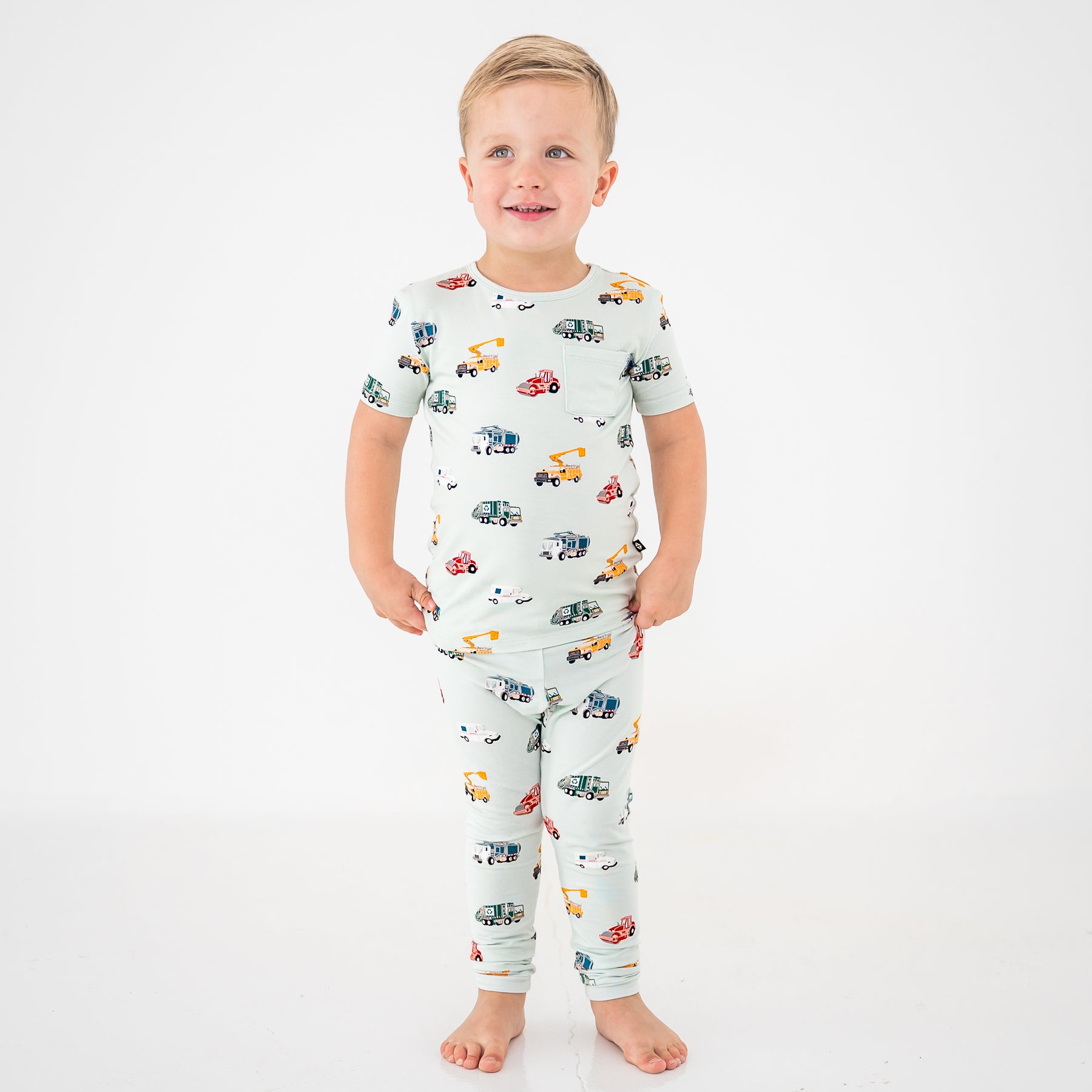 Young boy standing in front of a white background wearing the Short Sleeve with Pants Pajamas in City Vehicles