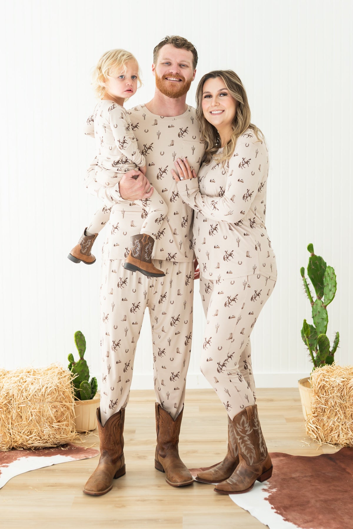 Family of three wearing matching Classic Cowboy pajamas and brown cowboy boots