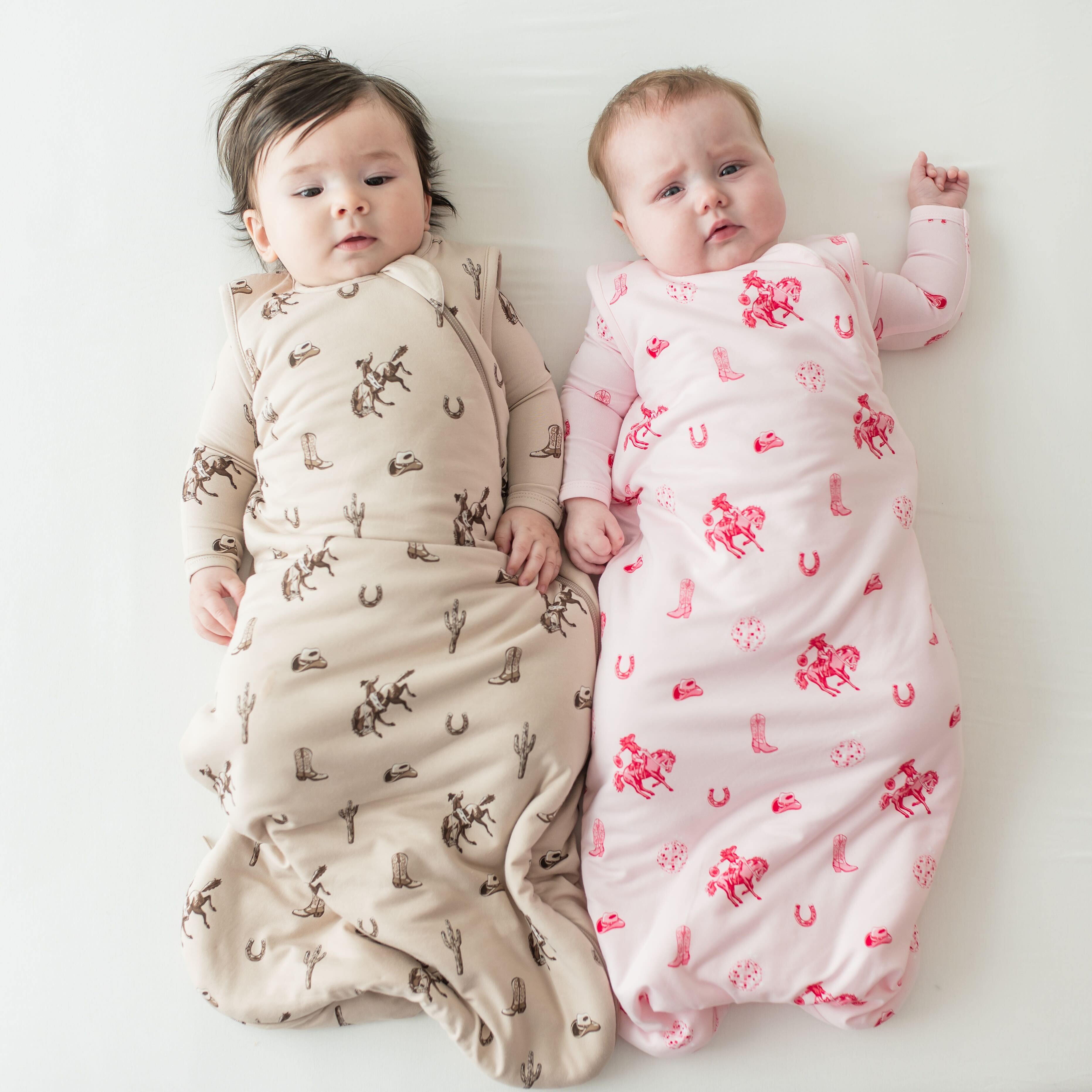 Two infants laying side by side wearing the sleep bags in the Classic Cowboy and Disco Cowgirl