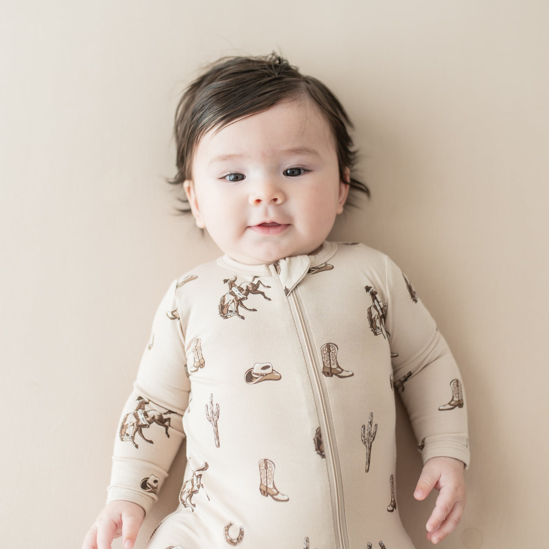 Close up of infant wearing the Zippered Romper in Classic Cowboy
