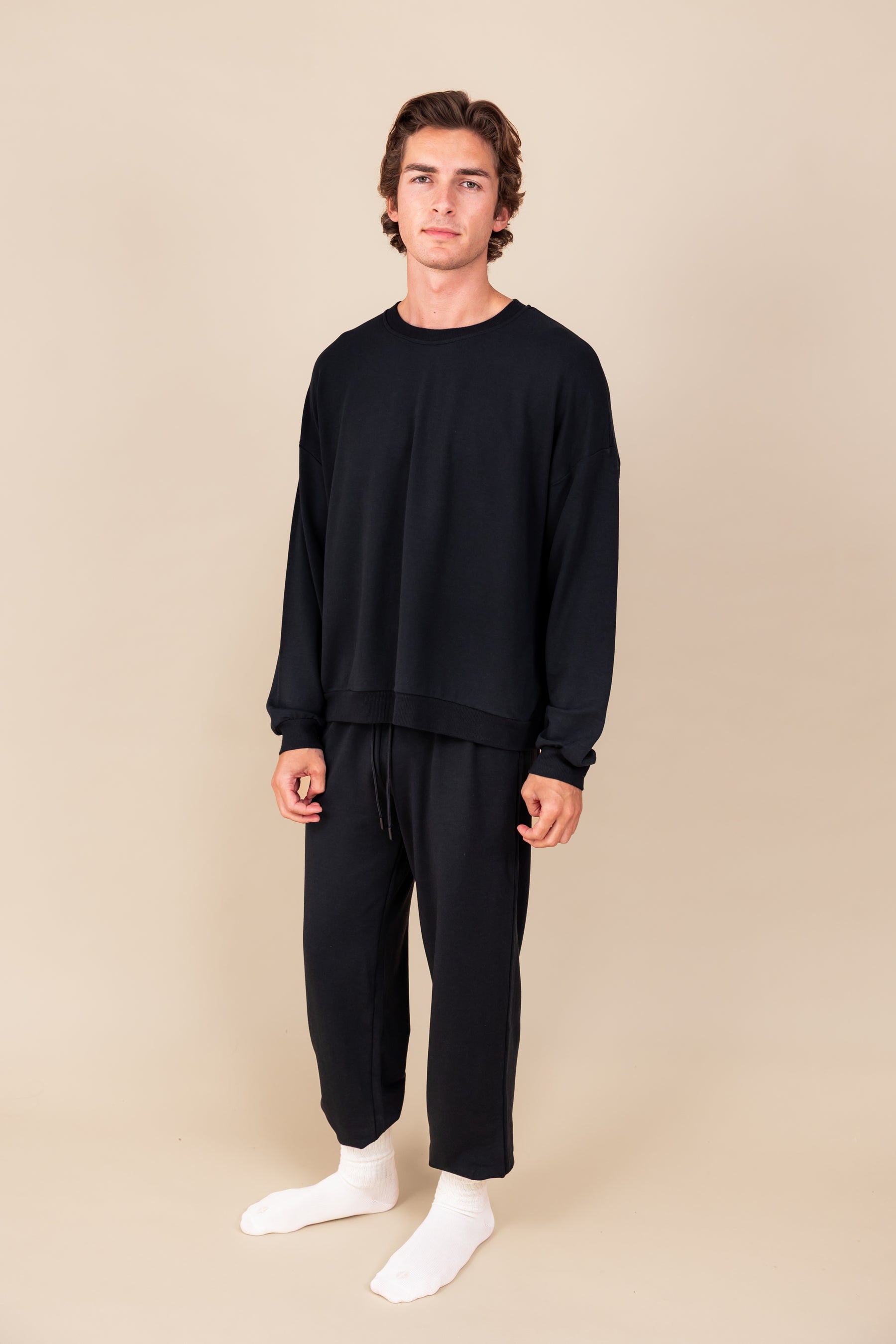 Modal wearing Adult Scrunch Socks in Cloud color on black jogger set on a beige background