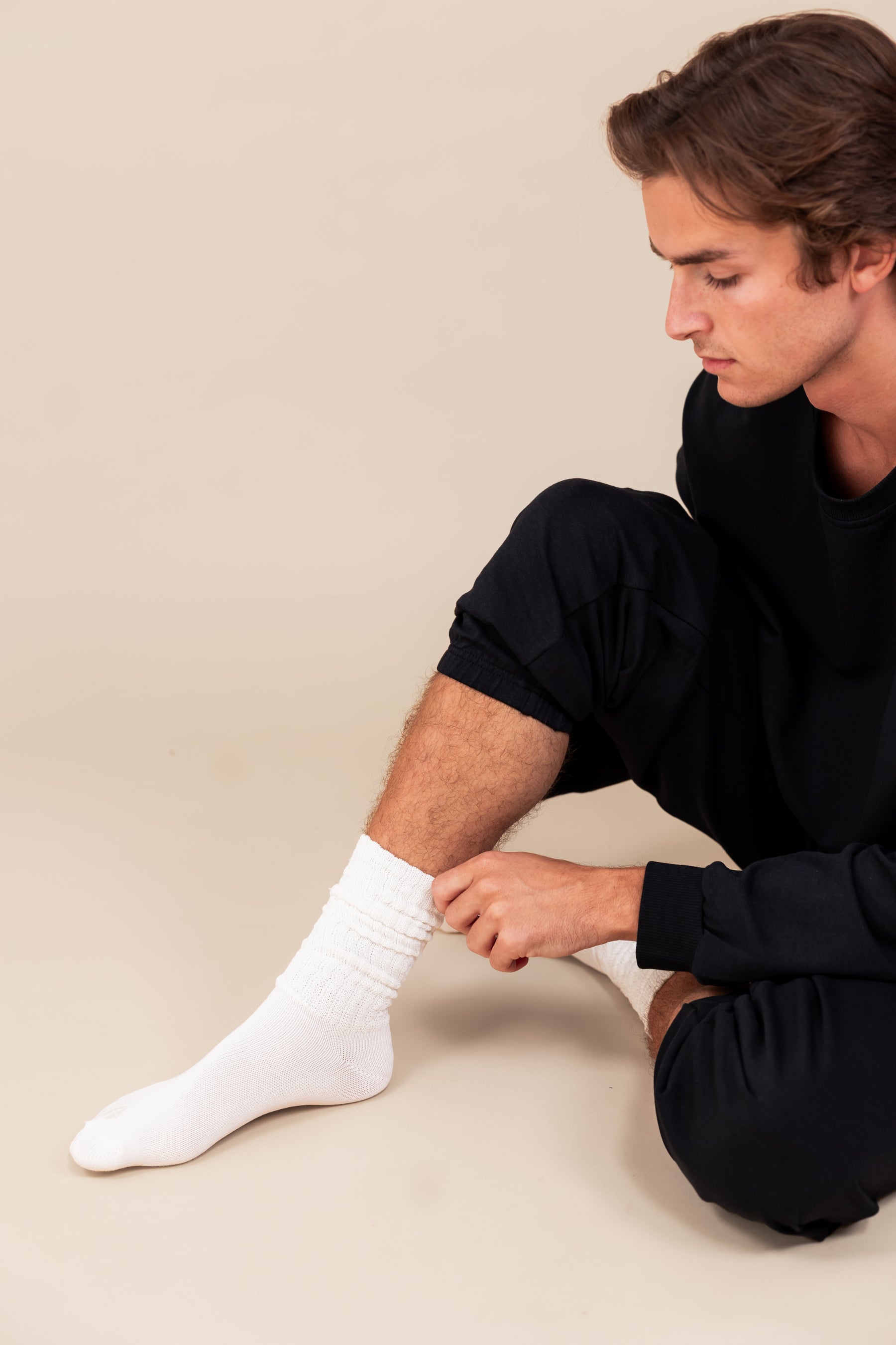 Modal wearing Adult Scrunch Socks in Cloud color while wearing black jogger set on a beige background