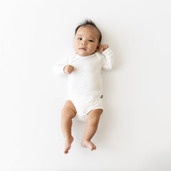 Baby in a white onesie lying on a white background
