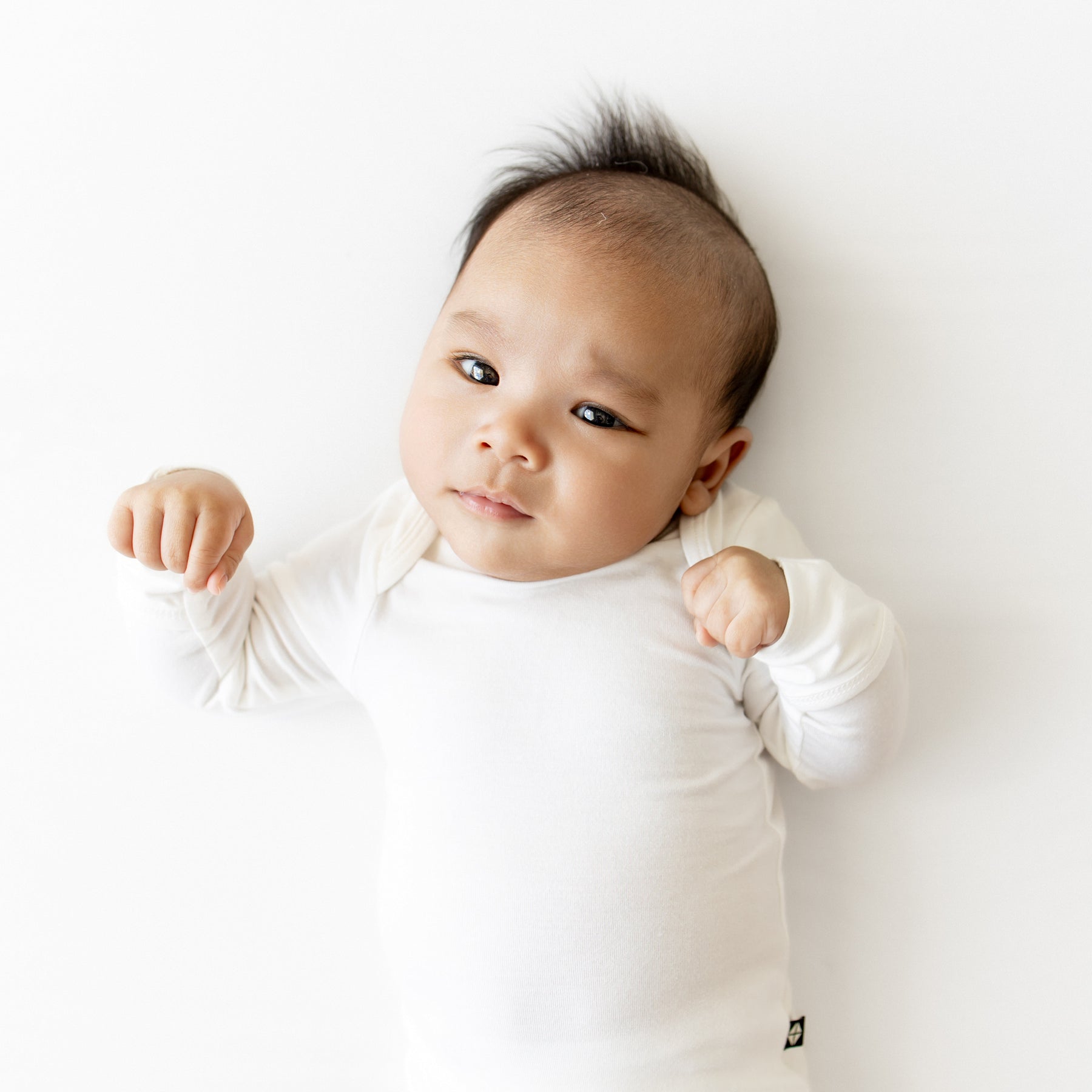 Baby wearing a white onesie on a plain background