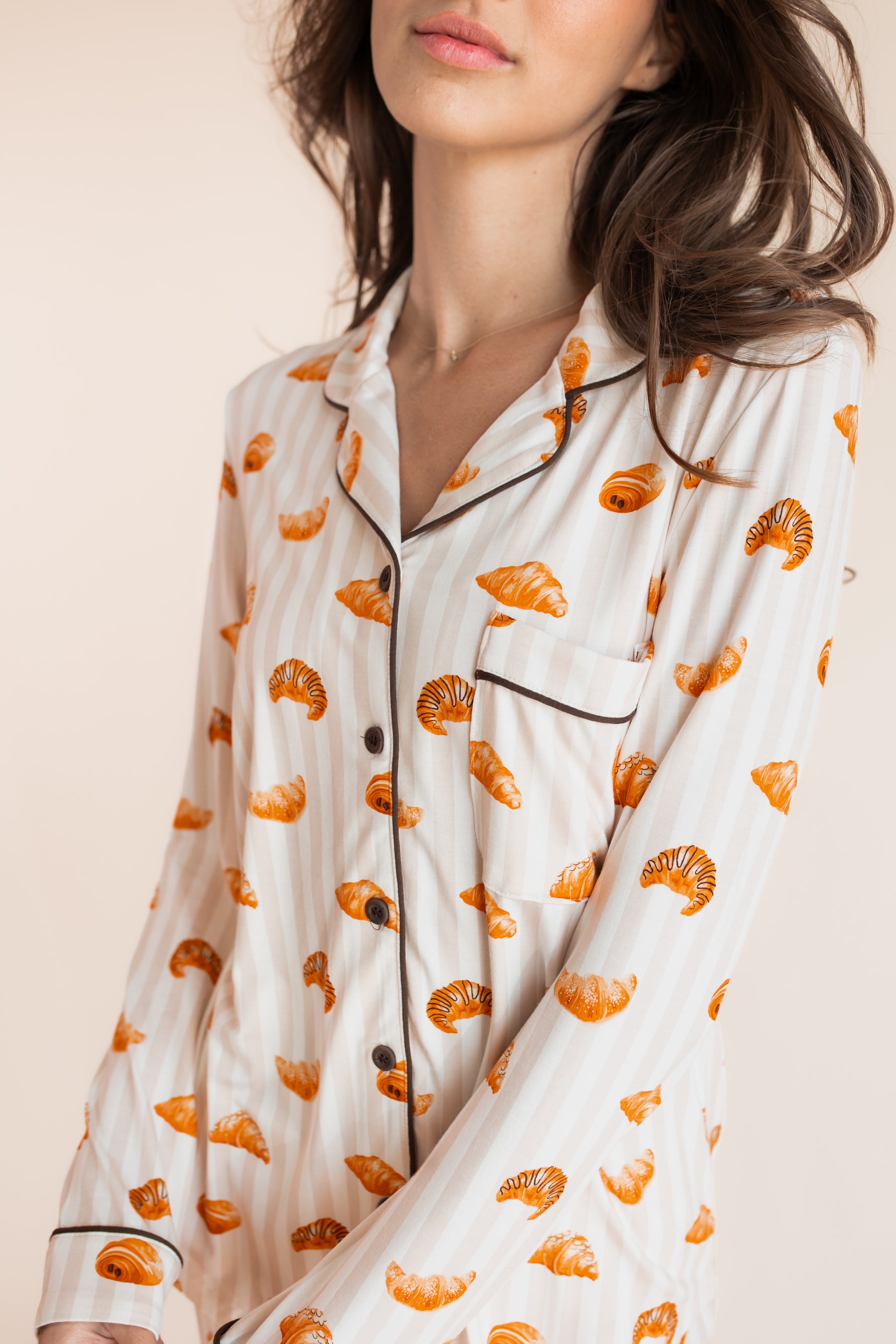 Close up of model wearing Long-Sleeved Women's Pajama Set with Croissant print on a beige background