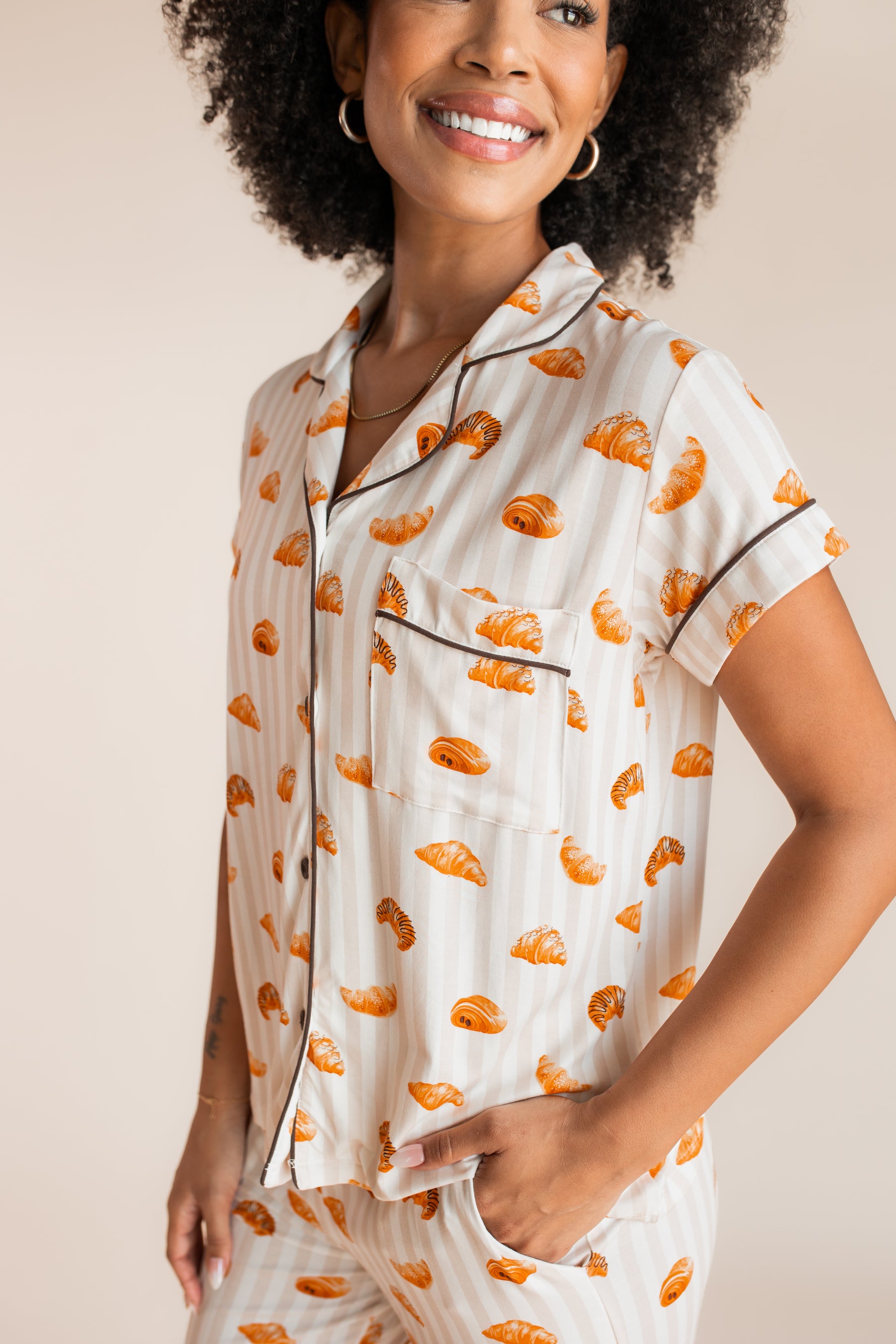 Close up of Model wearing Women's Short Sleeve Cropped Pajama Set with Croissant print on a beige background